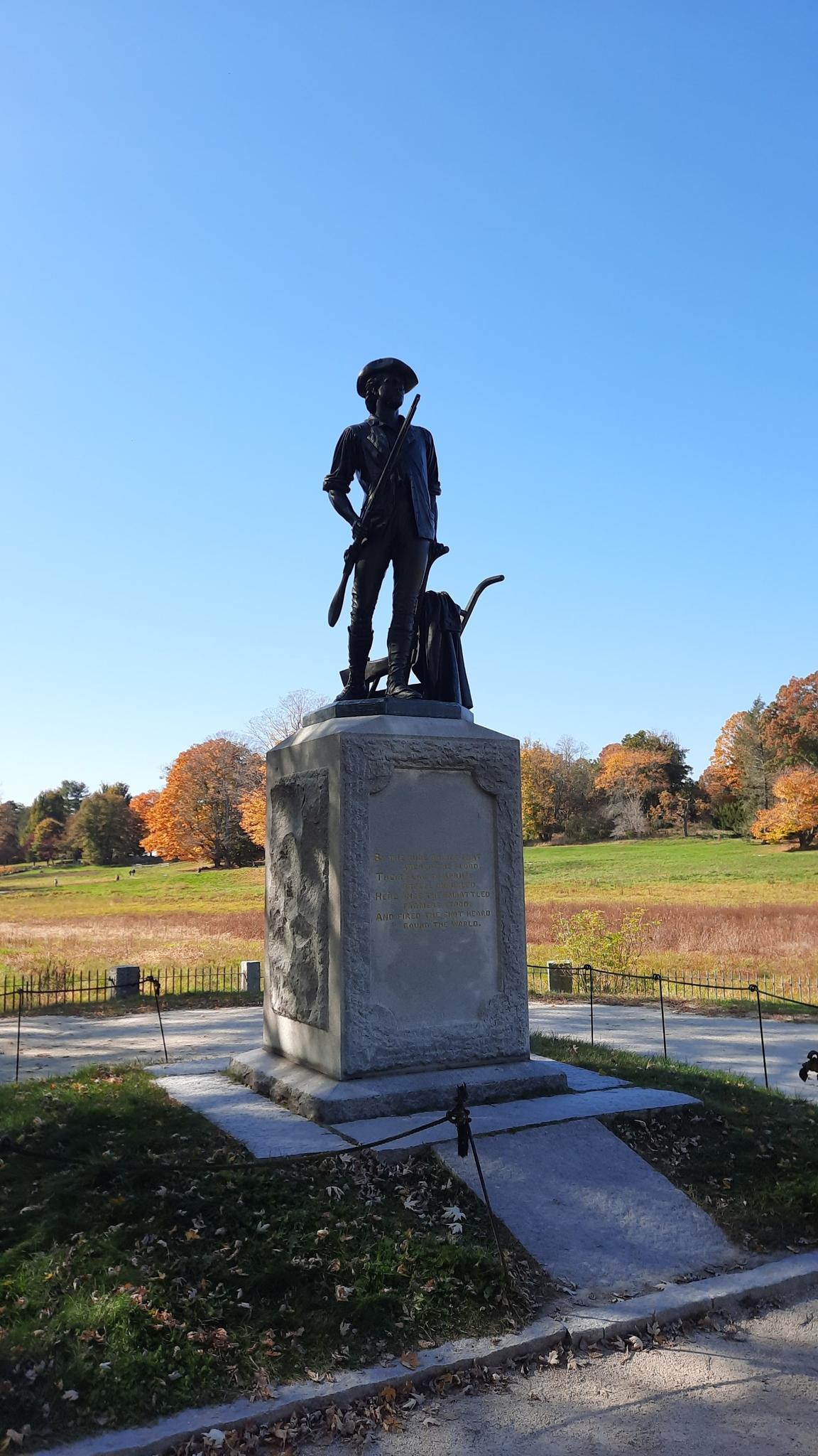 A bronze statue of a person with a rifle on a stone pedestal.