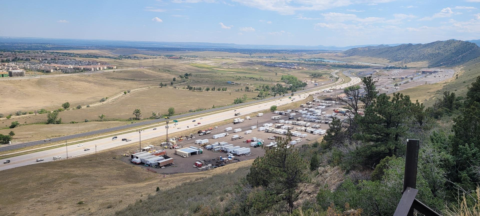 Wide view of a highway, parking lot, and distant hills.