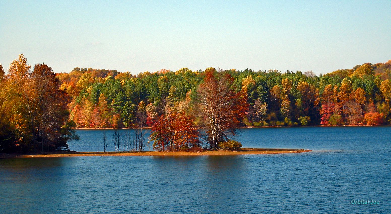 Vibrant autumn trees line a clear blue lake under a bright sky. - Liberty Reservoir Shervettes Corner Loop