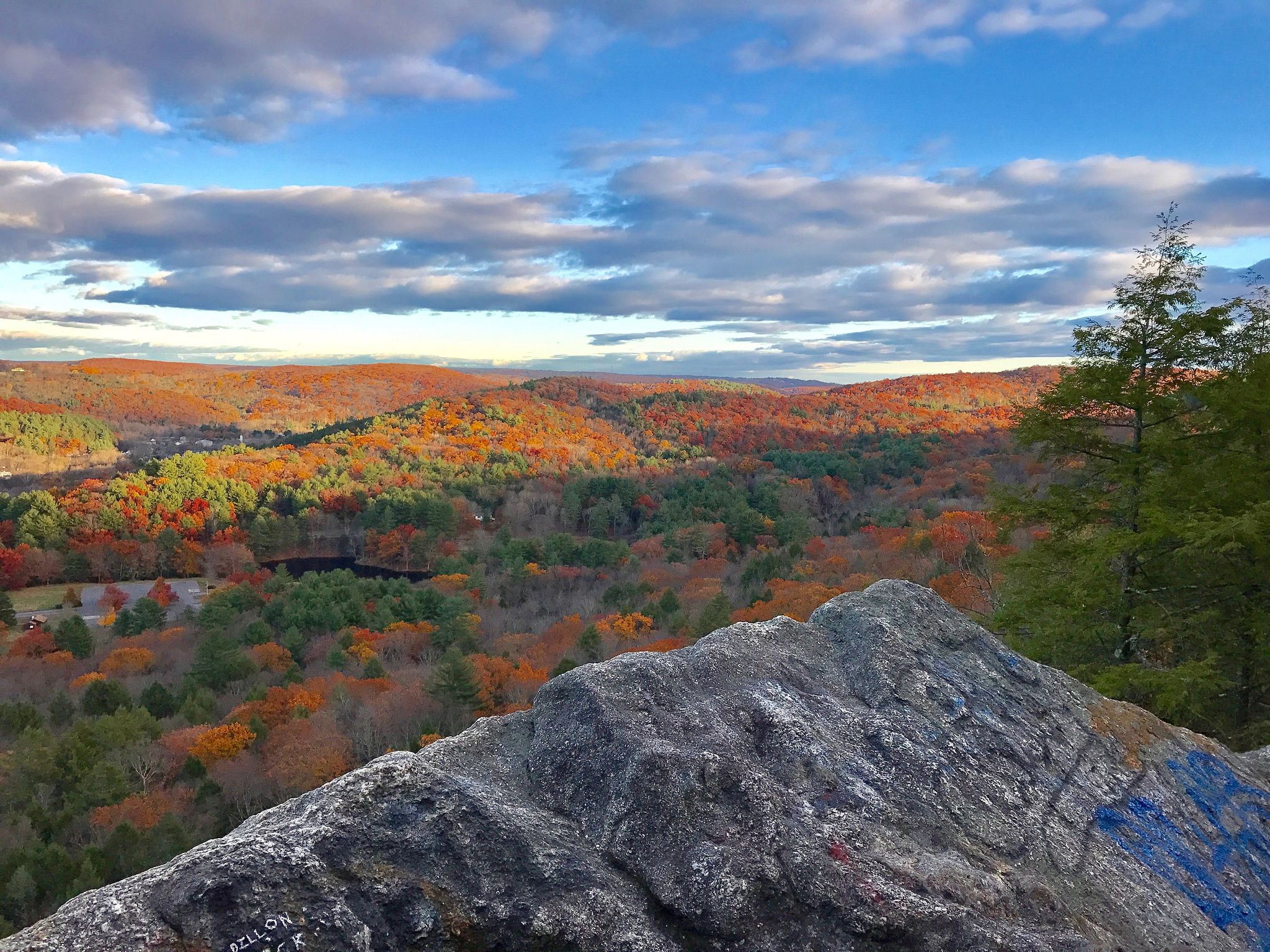Panoramic autumn forest view from a rocky outcrop under a partly cloudy sky. - Black Rock Trail
