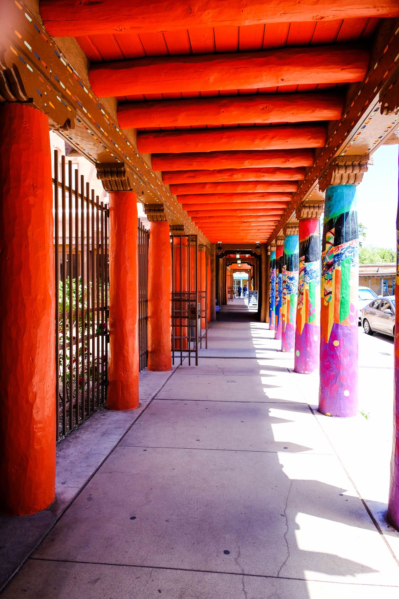 Long, sunny outdoor corridor with vibrant orange and colorful pillars and a paved walkway. - La Tierra Trails Loop from Santa Fe