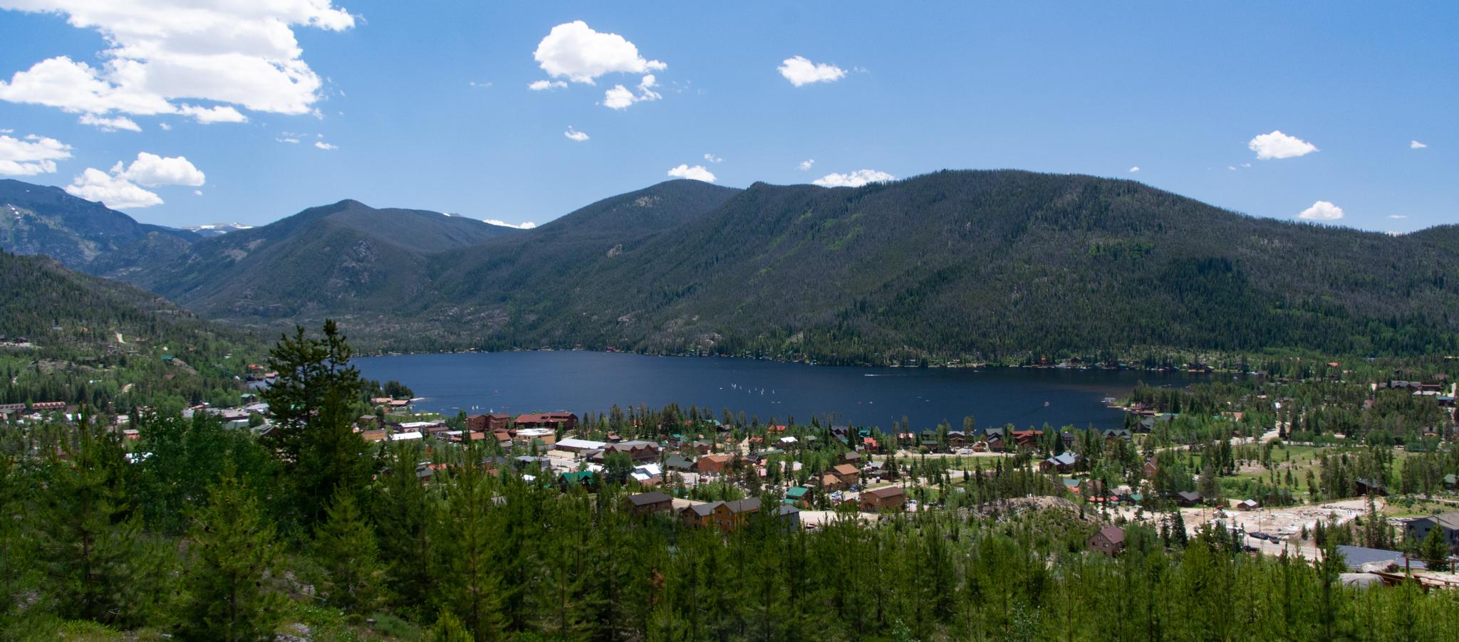 Panoramic view of a lake and town nestled in a mountain valley.