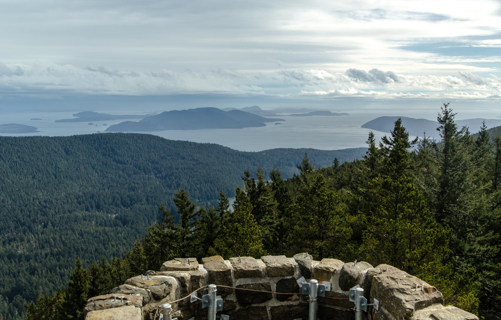 Panoramic mountain view over islands and water under a cloudy sky.