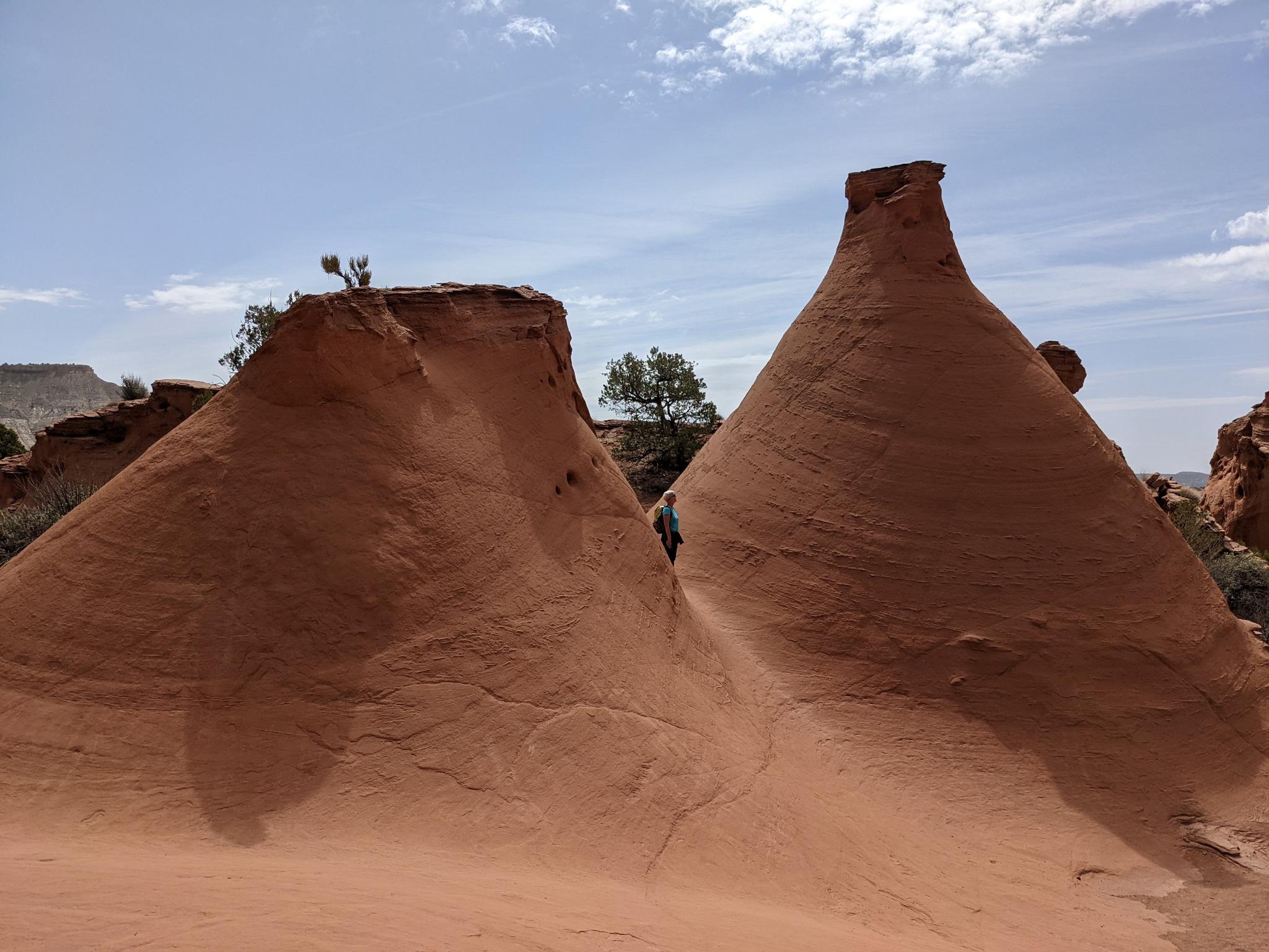 Two large, conical red rock formations under a partly cloudy sky.