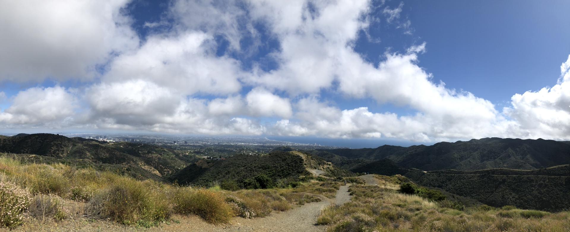Wide panoramic view of distant city and hills with a winding dirt path.