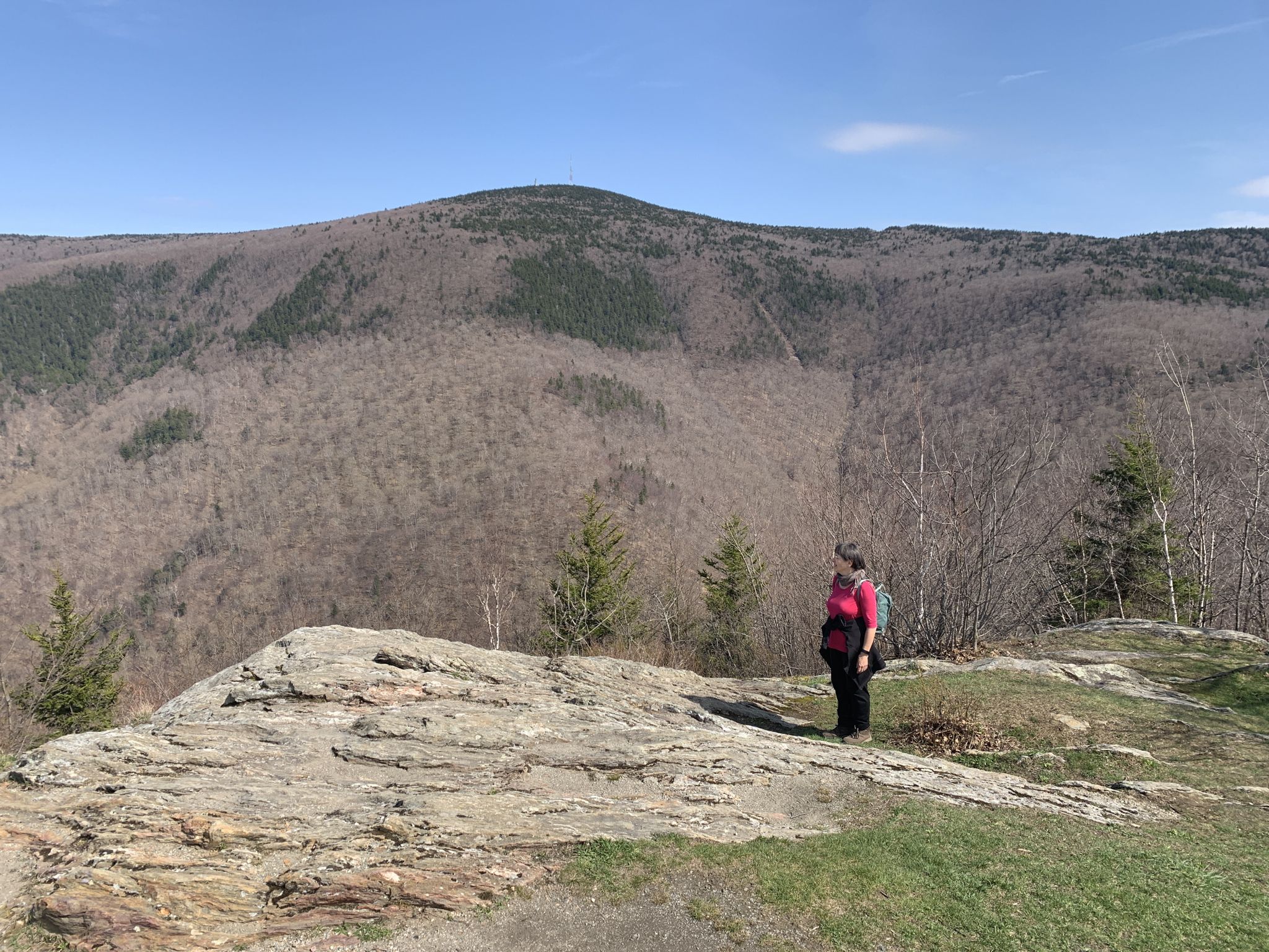 Woman with backpack stands on a rocky cliff overlooking vast mountains. - Stony Ledge via Haley Farm and Hopper Trails Loop