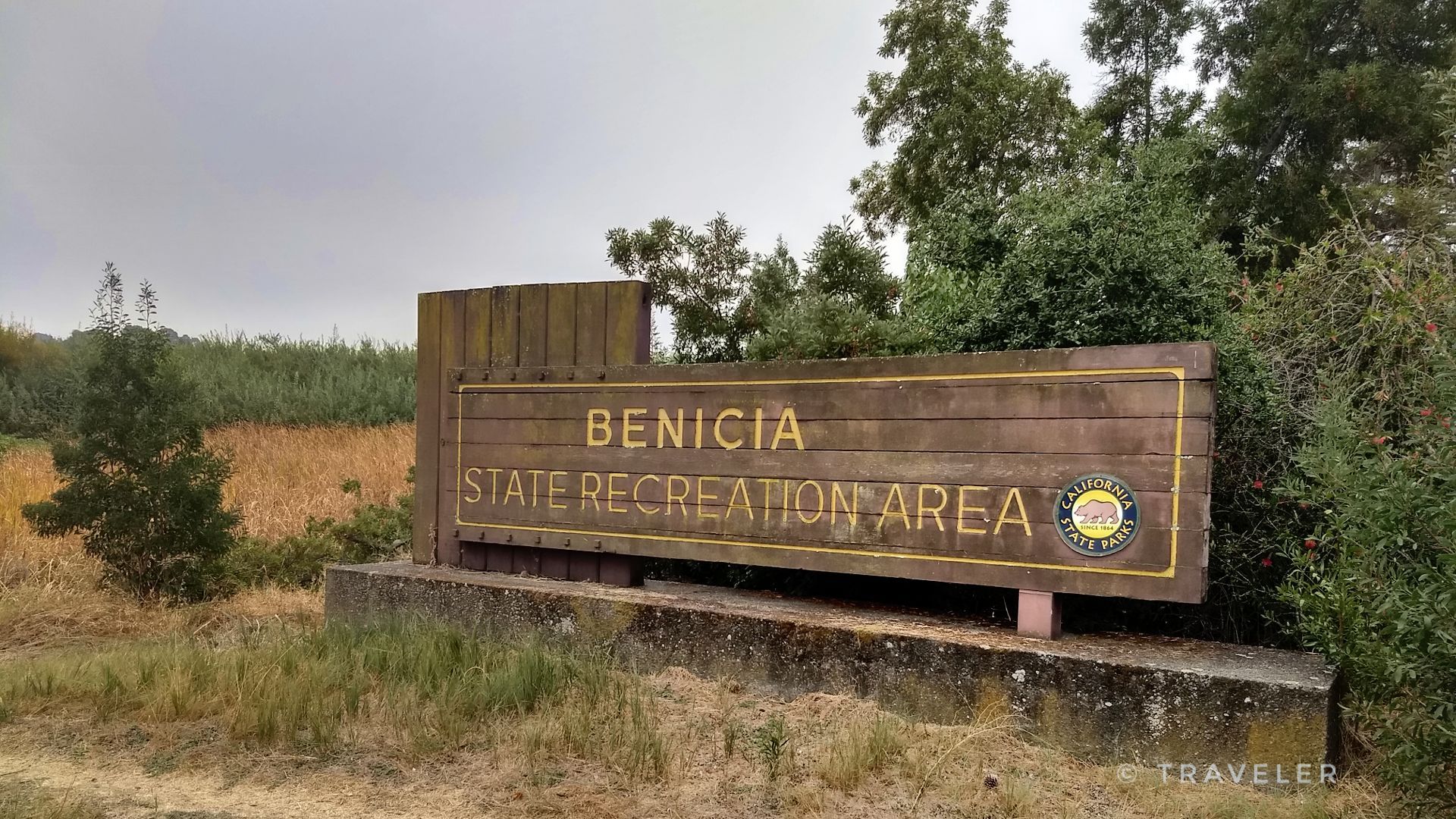 A large wooden sign stands among trees and dry grass on an overcast day. - Carquinez Strait and Mike Taugher Trail Loop