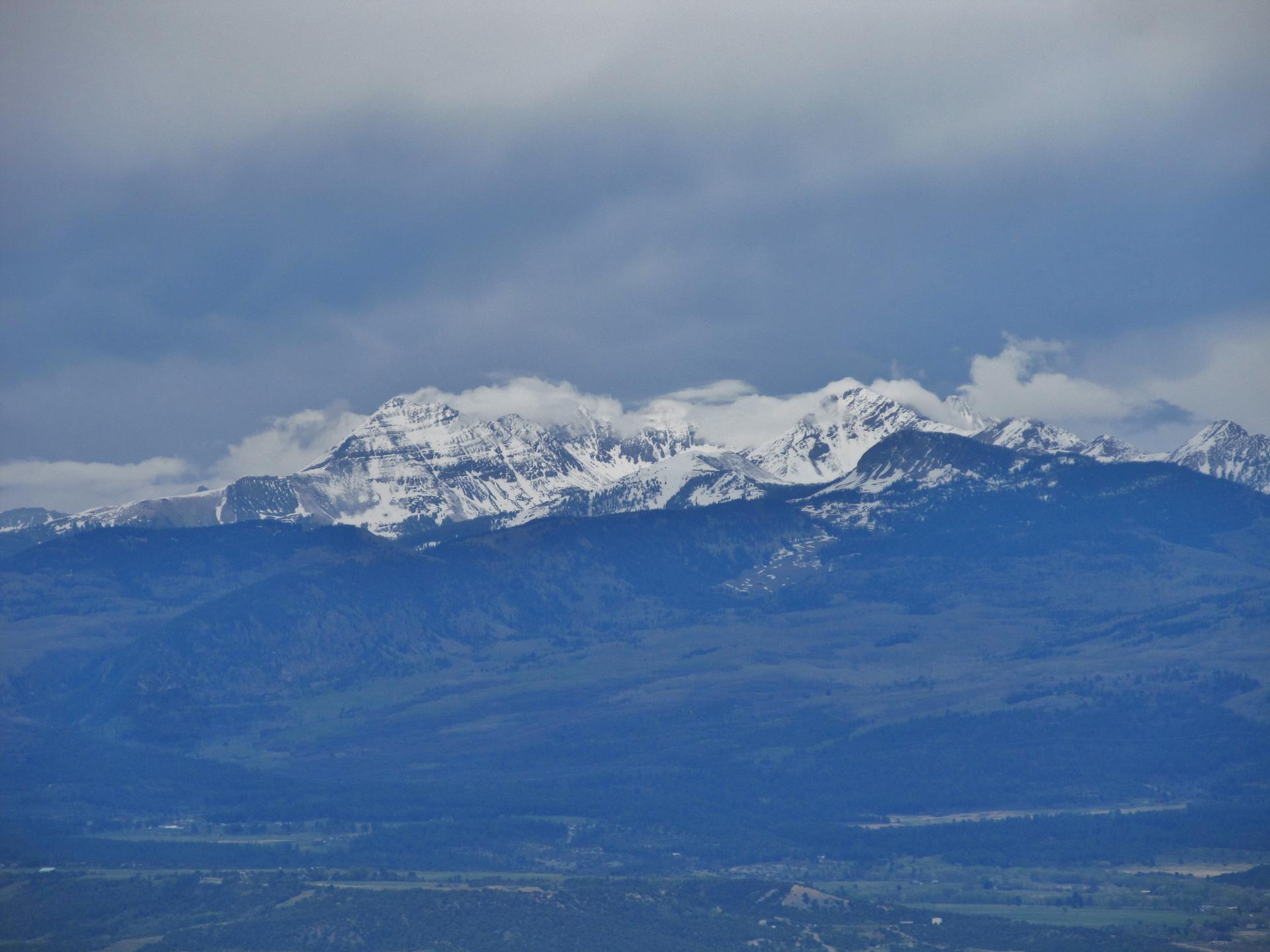 Distant snow-capped mountains under a cloudy sky, with lower hills.