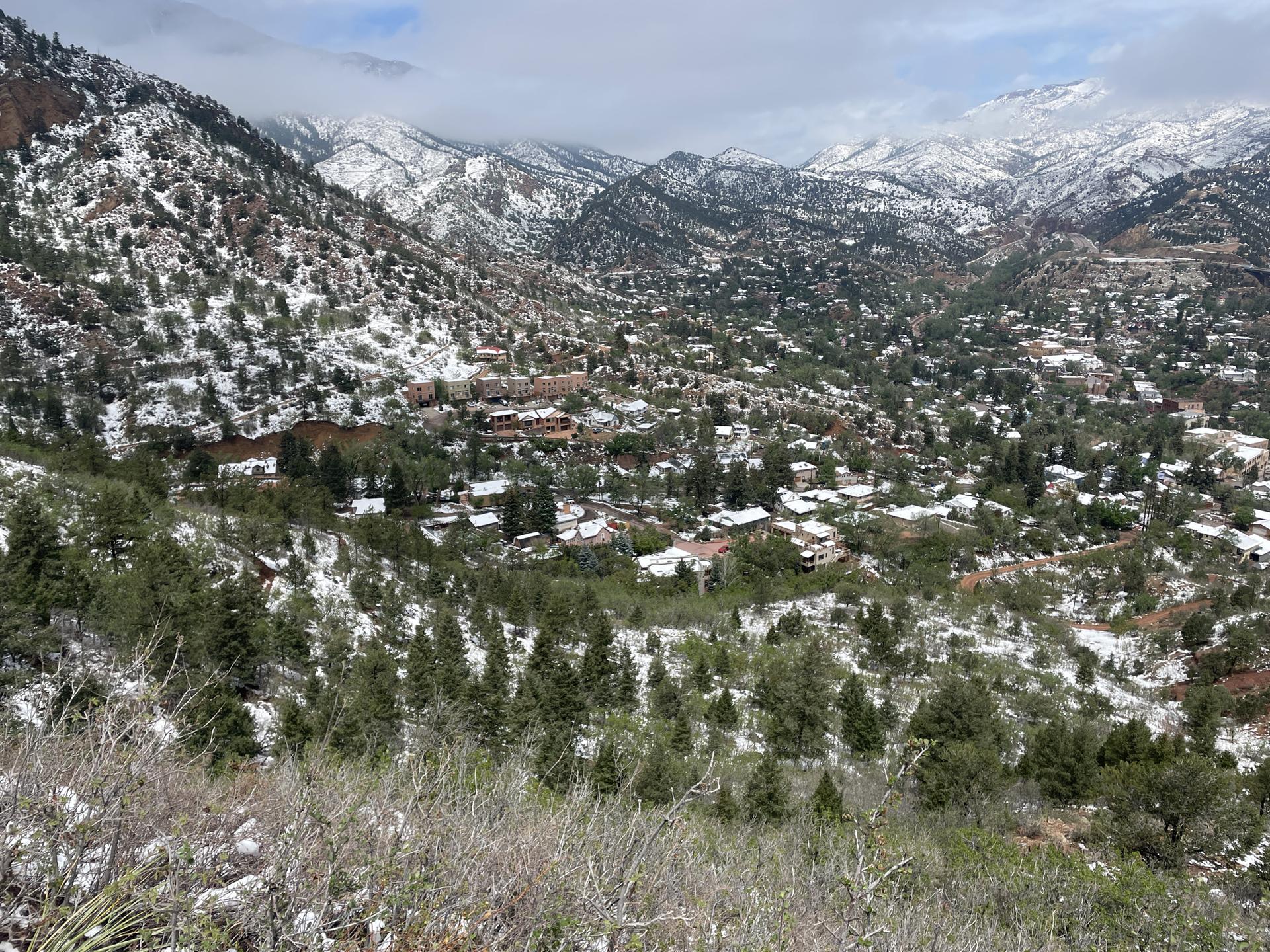 Overhead view of a snow-dusted town in a mountain valley under cloudy skies.