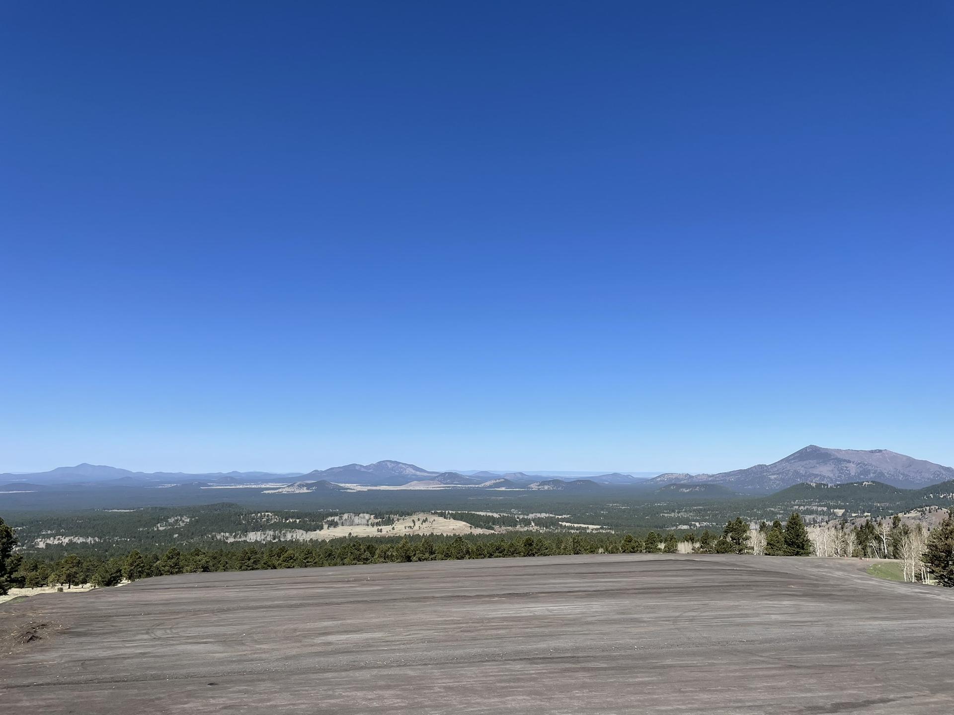 Wide panoramic view of distant mountains and forests under a clear blue sky.