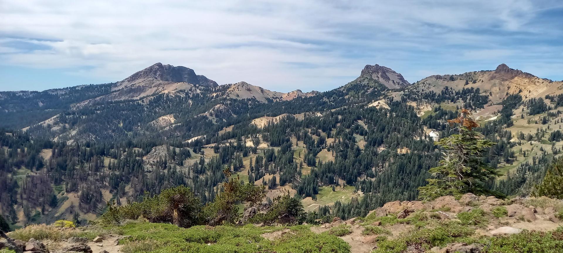 Forested mountains and valleys under a partly cloudy sky.