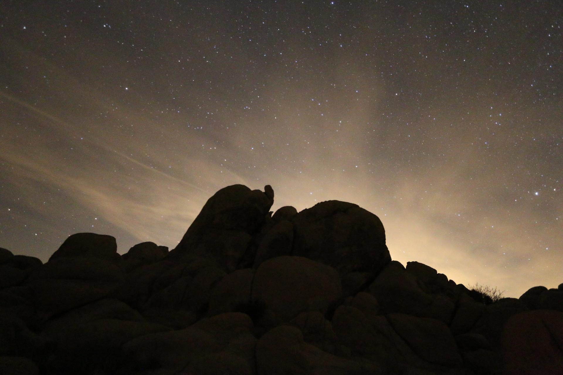 Silhouetted rock formations under a vast, star-filled night sky.