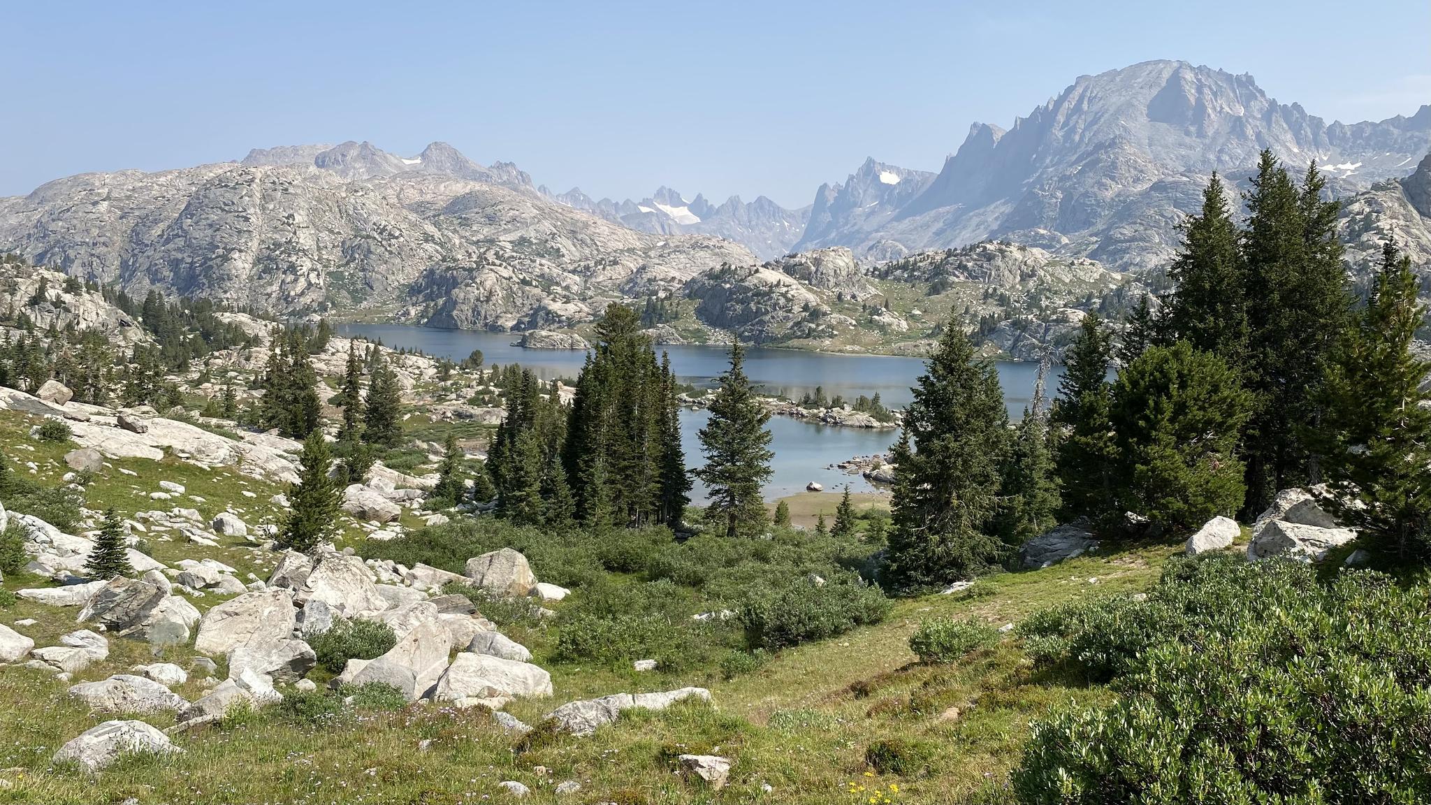 Panoramic view of multiple lakes and rugged mountains, clear blue sky.