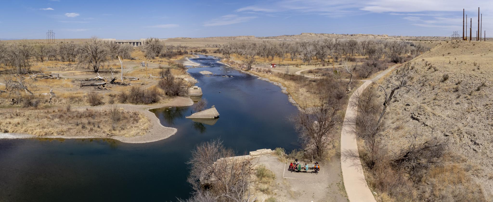 Panoramic view of a wide river winding through a dry, treed landscape.