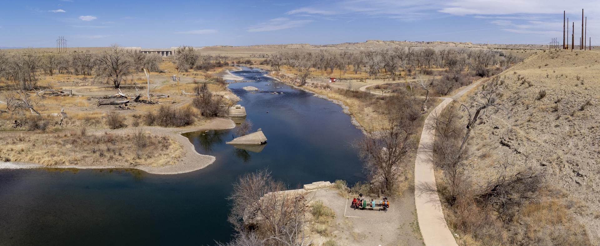Panoramic view of a wide river winding through a dry, treed landscape.