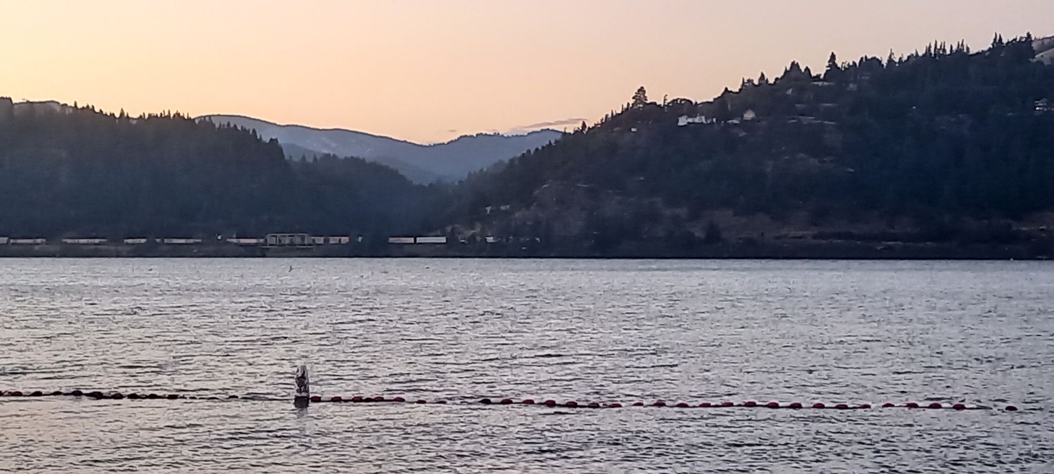 Wide body of water with buoys, distant forested hills, and soft evening light. - Hood River Waterfront