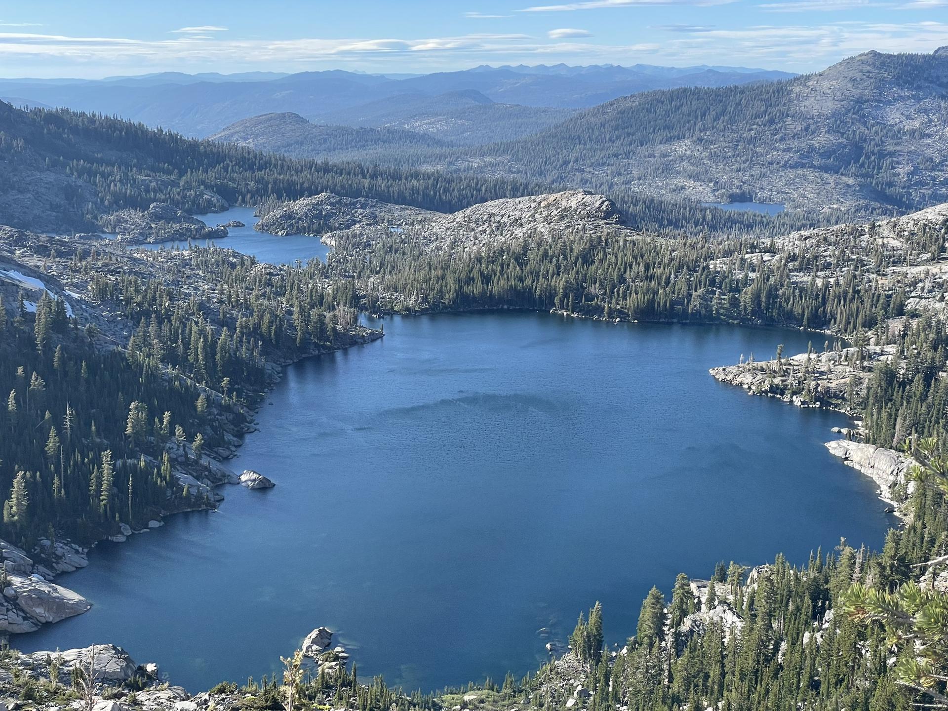 Multiple blue mountain lakes surrounded by dense pine forests and rocky slopes.