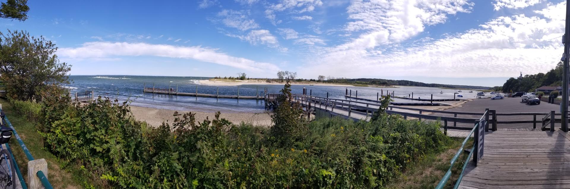 Panoramic view of a bay with multiple docks, a sandy beach, and blue sky.
