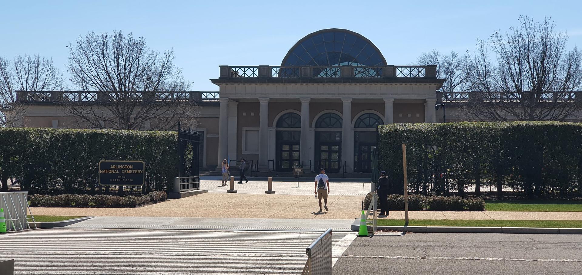 Large classical building with a domed roof and people walking in front.