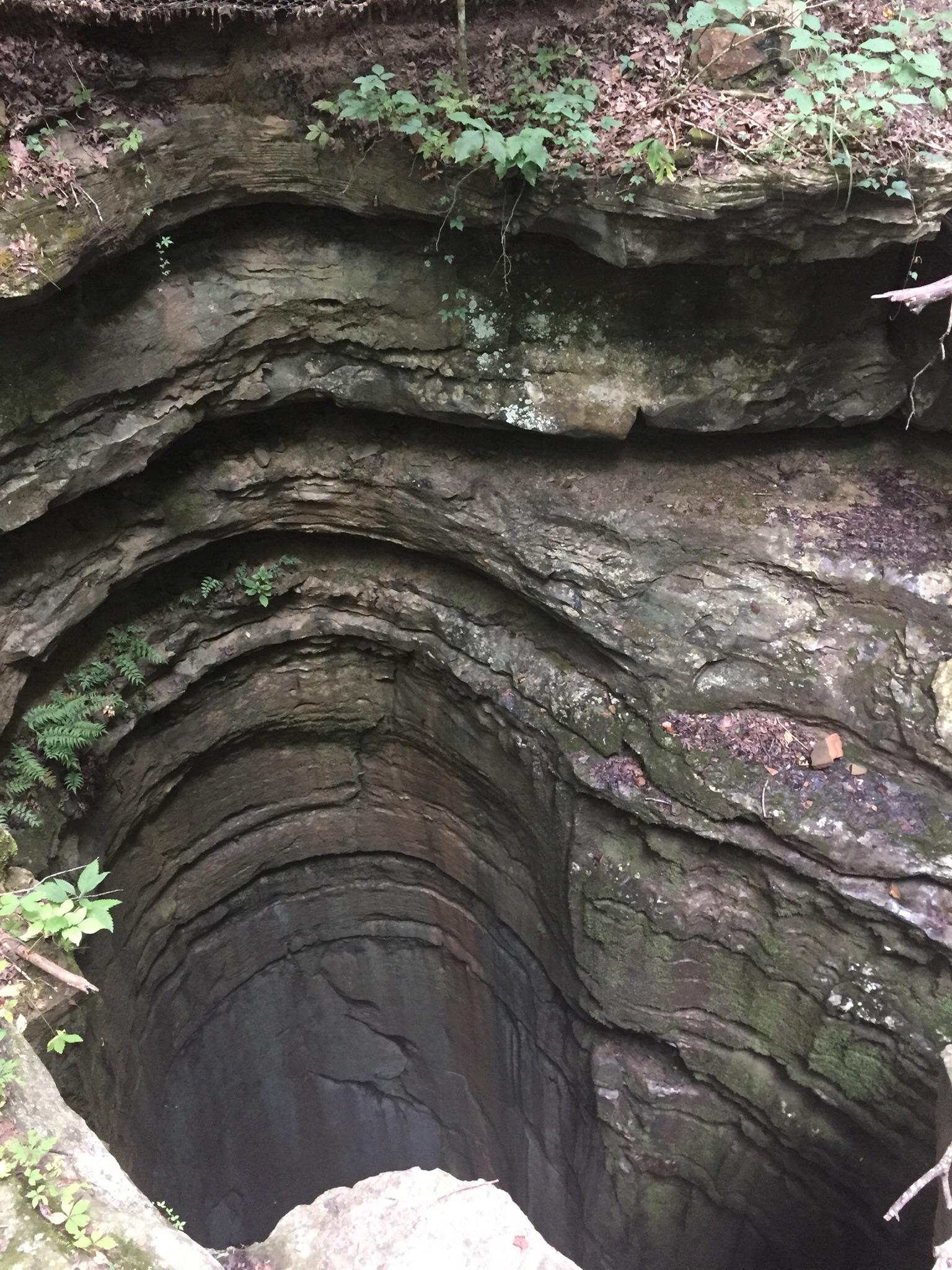 Deep, layered rock formation with curved walls, possibly a cave entrance.