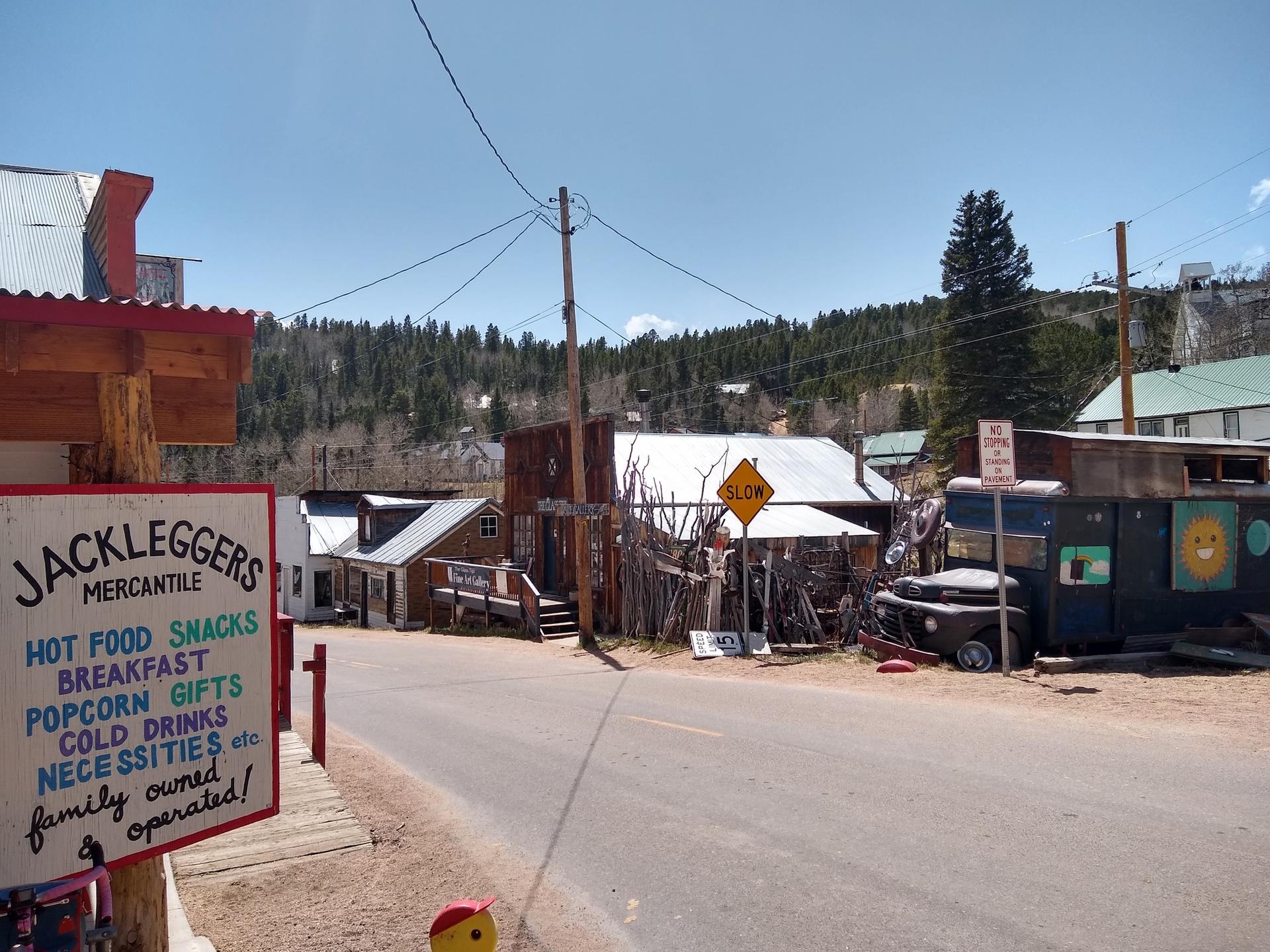 Rustic mercantile store sign on a sunny street with old wooden buildings.