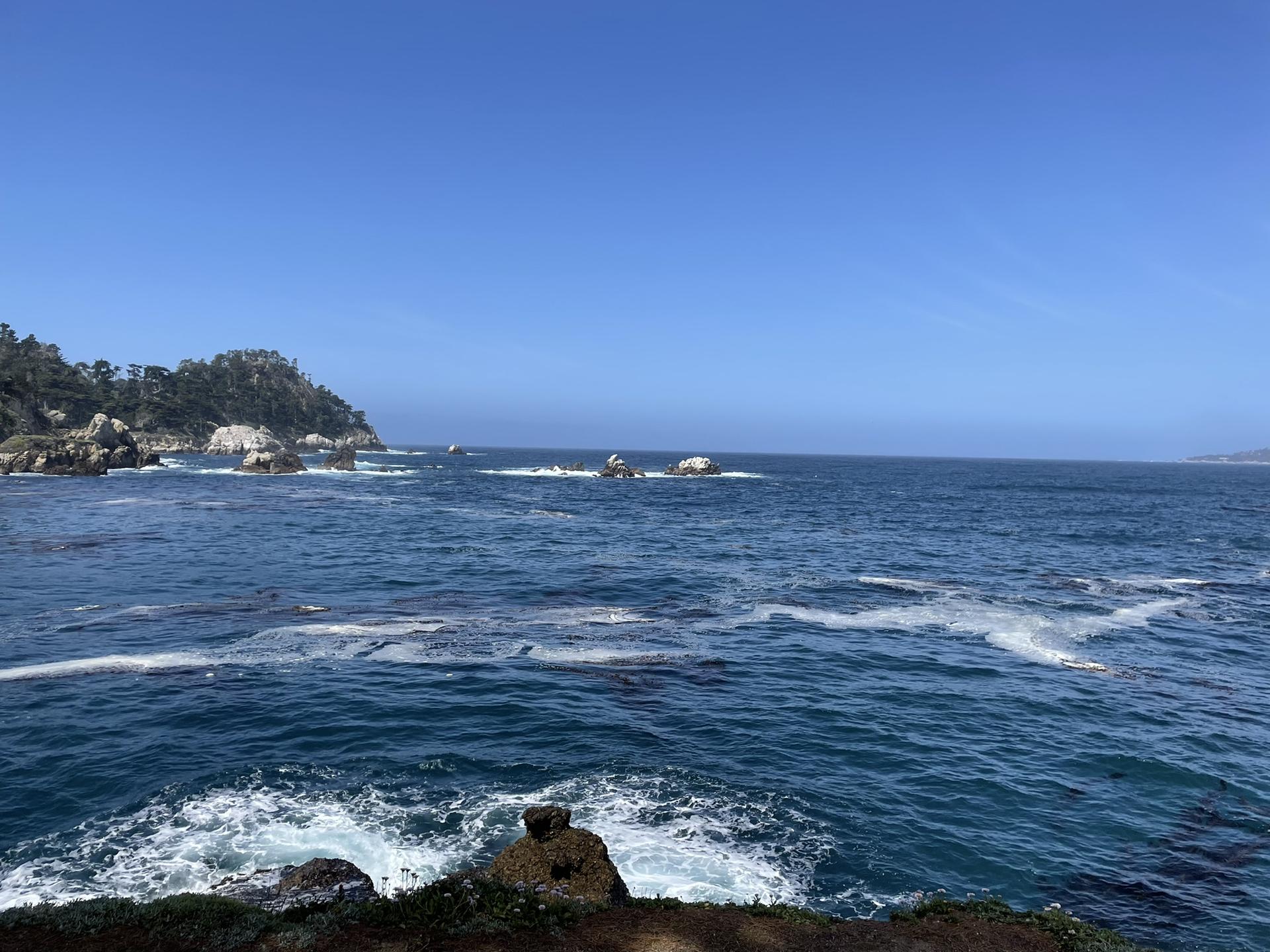 Expansive deep blue ocean with whitecaps and distant rocky coastal formations.