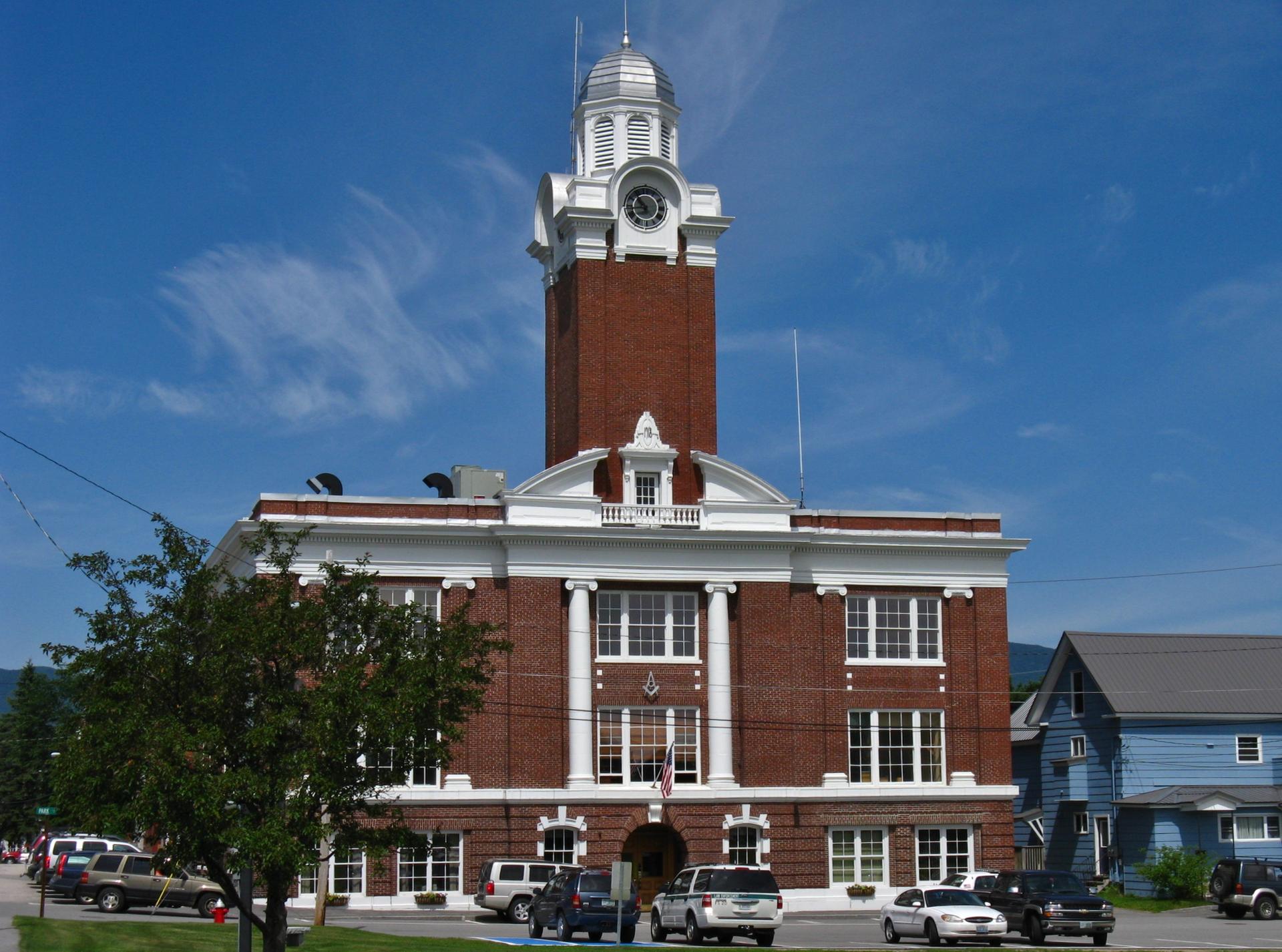 Large brick building with a clock tower under a bright blue sky.