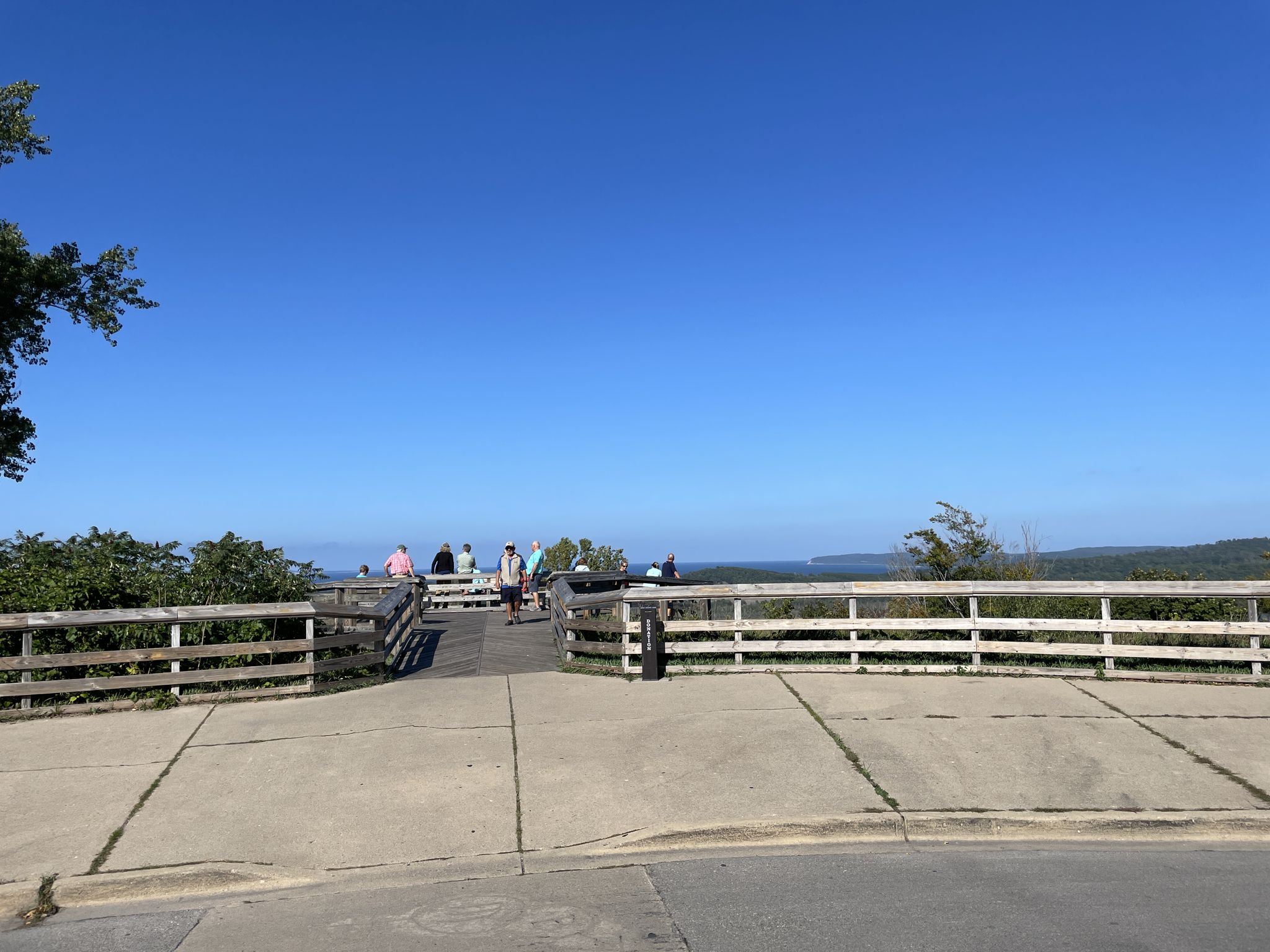 People on a wooden observation deck overlooking distant water under a clear sky. - Cottonwood Trail