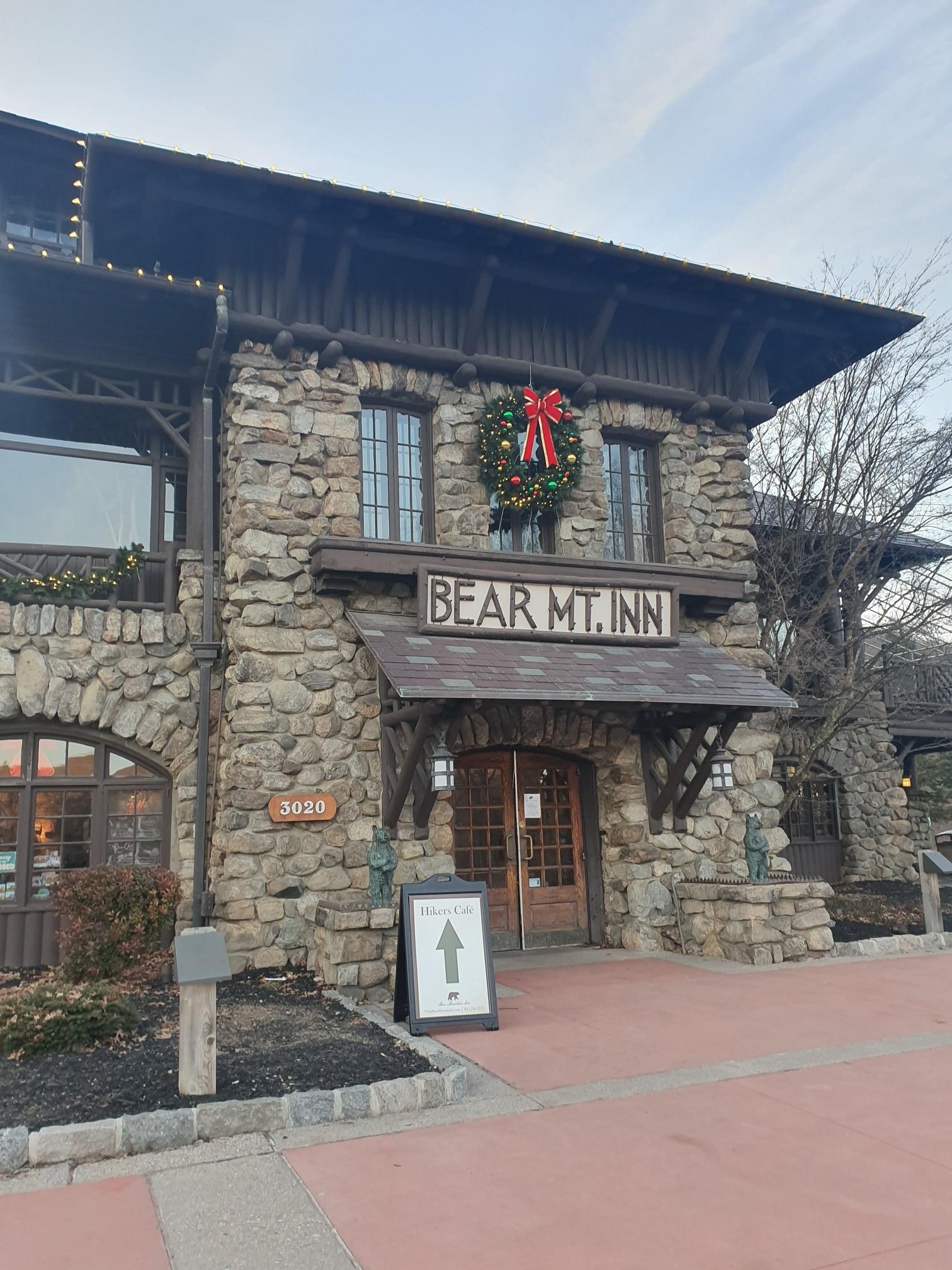 Large stone building with a festive wreath and "Inn" sign on an overcast day.