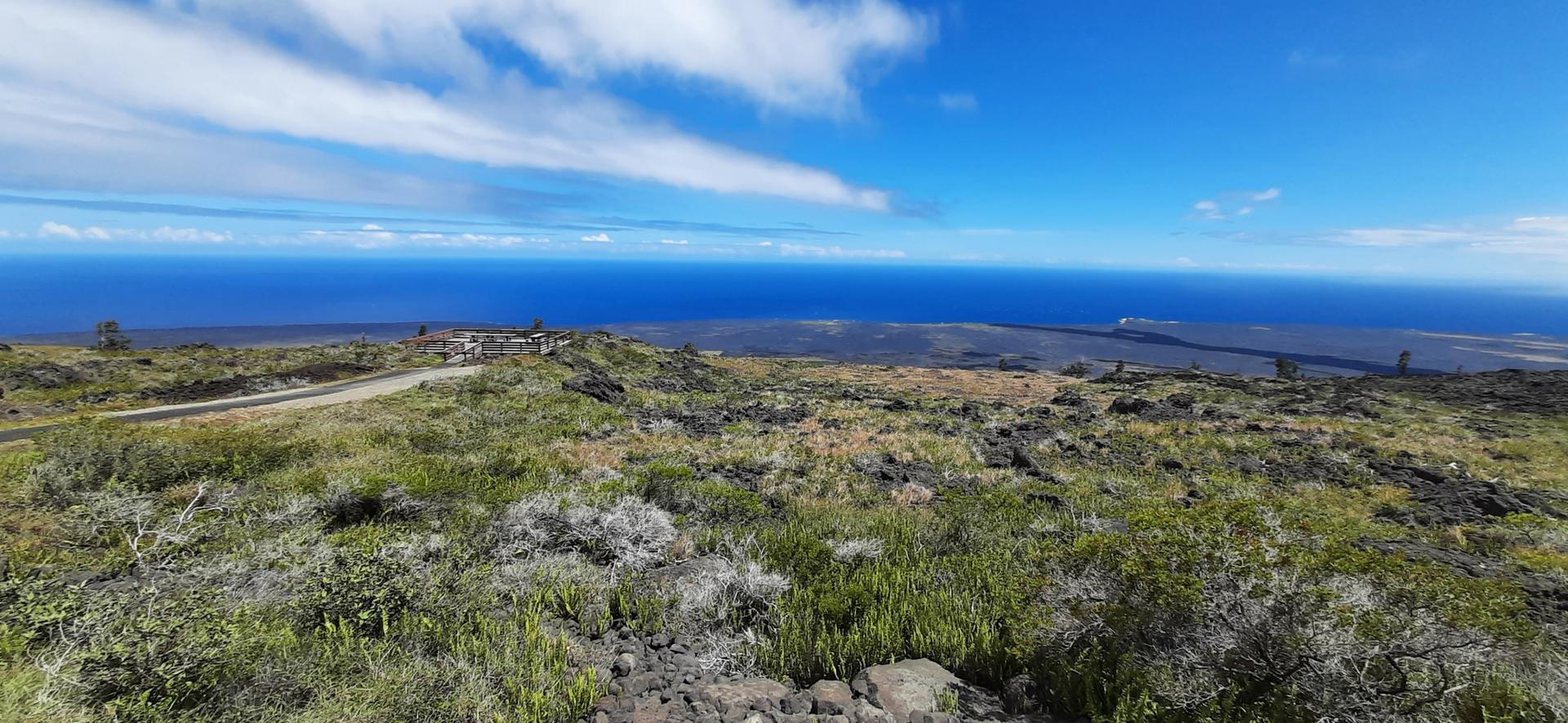 Panoramic view of a rocky, sparse landscape meeting a vast blue ocean.