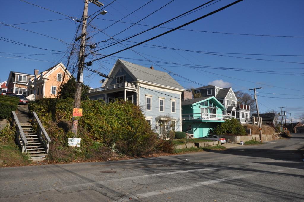 Colorful houses on a hillside street with utility poles and wires.