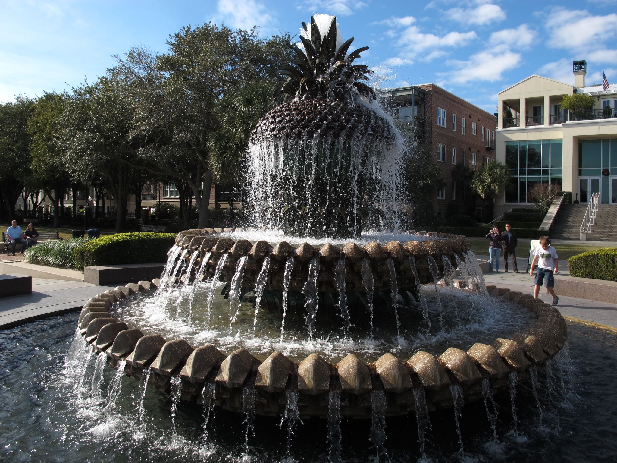 Large pineapple fountain spraying water in a sunny park with people. - Waterfront Park – White Point Garden loop from Charleston