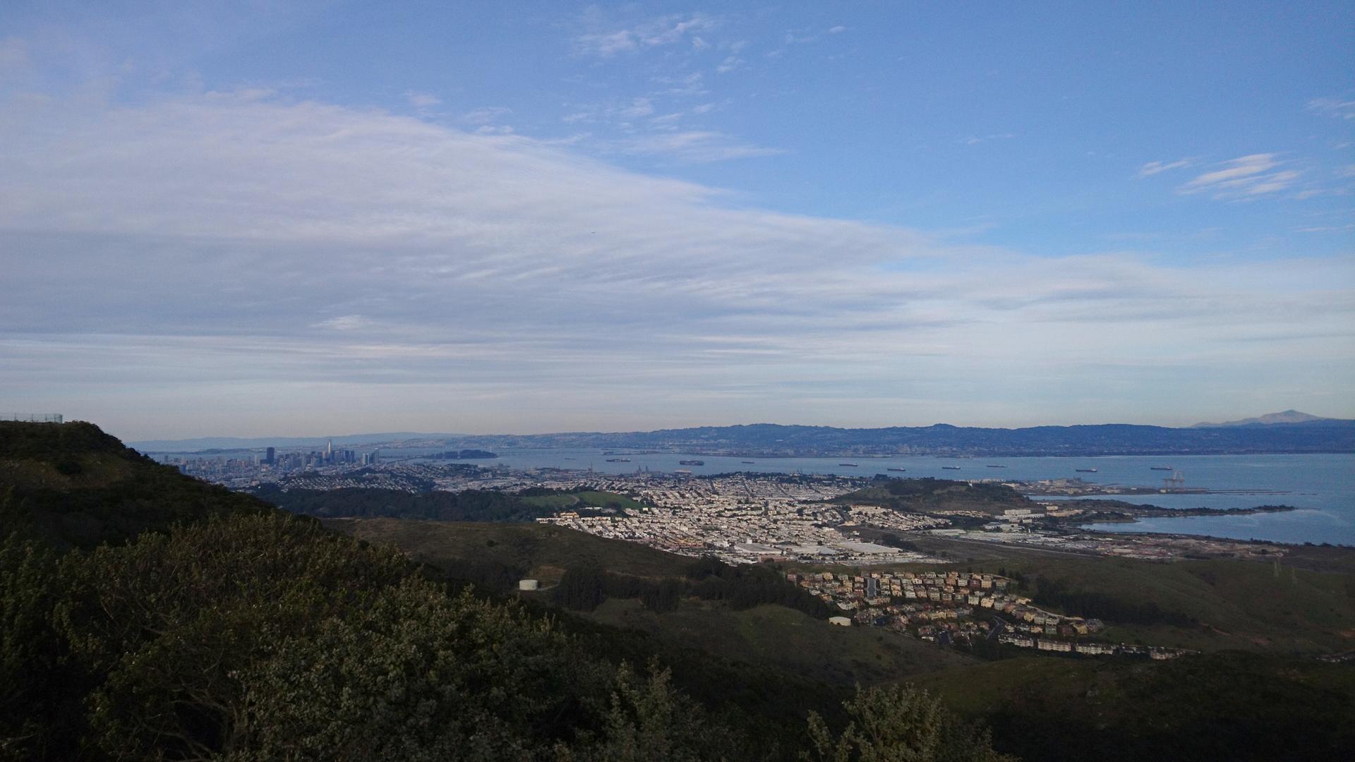 Panoramic view of a city and bay under a cloudy sky.