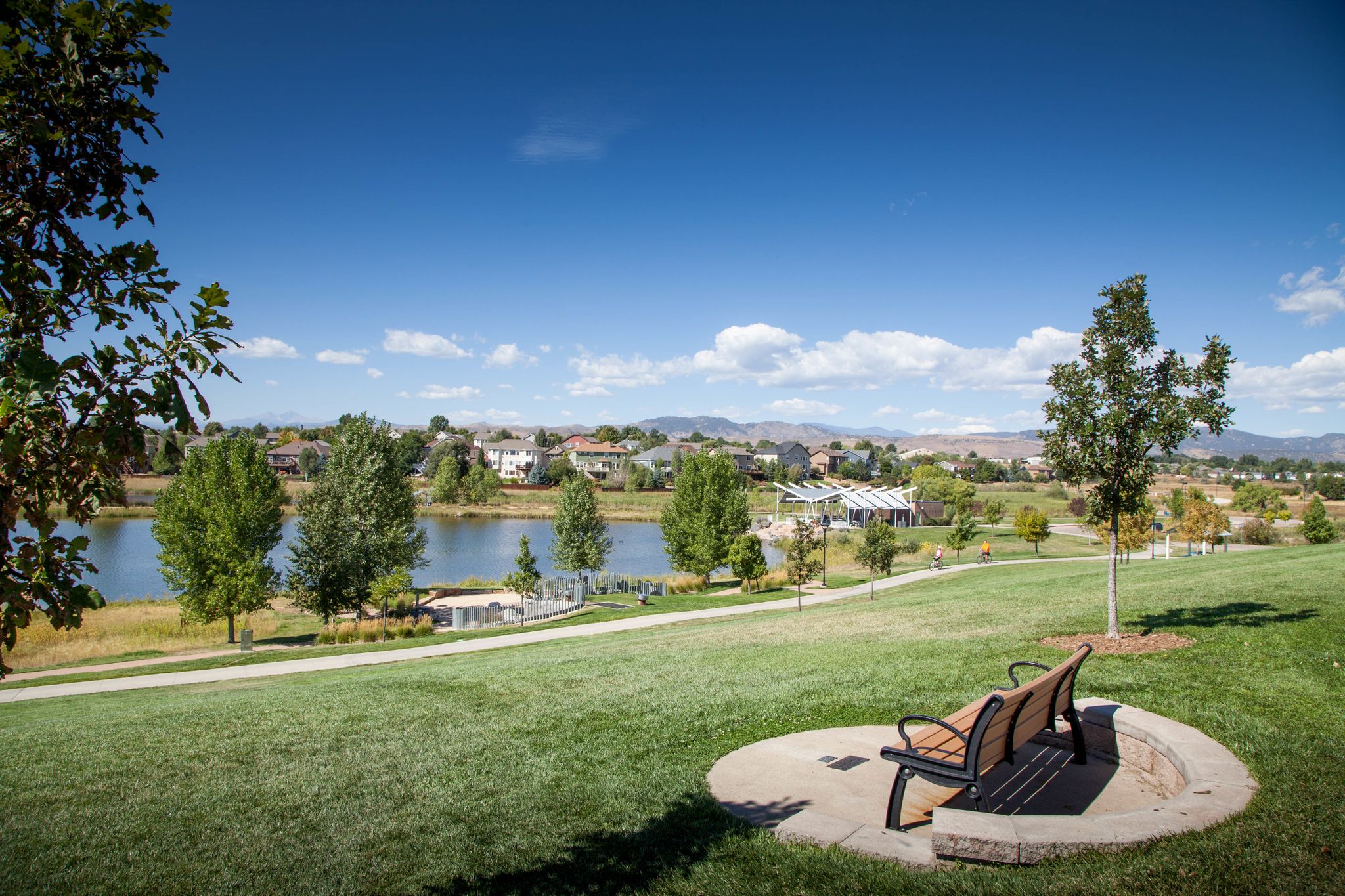Park bench on a grassy hill overlooking a lake and distant town. - Carter Lake loop