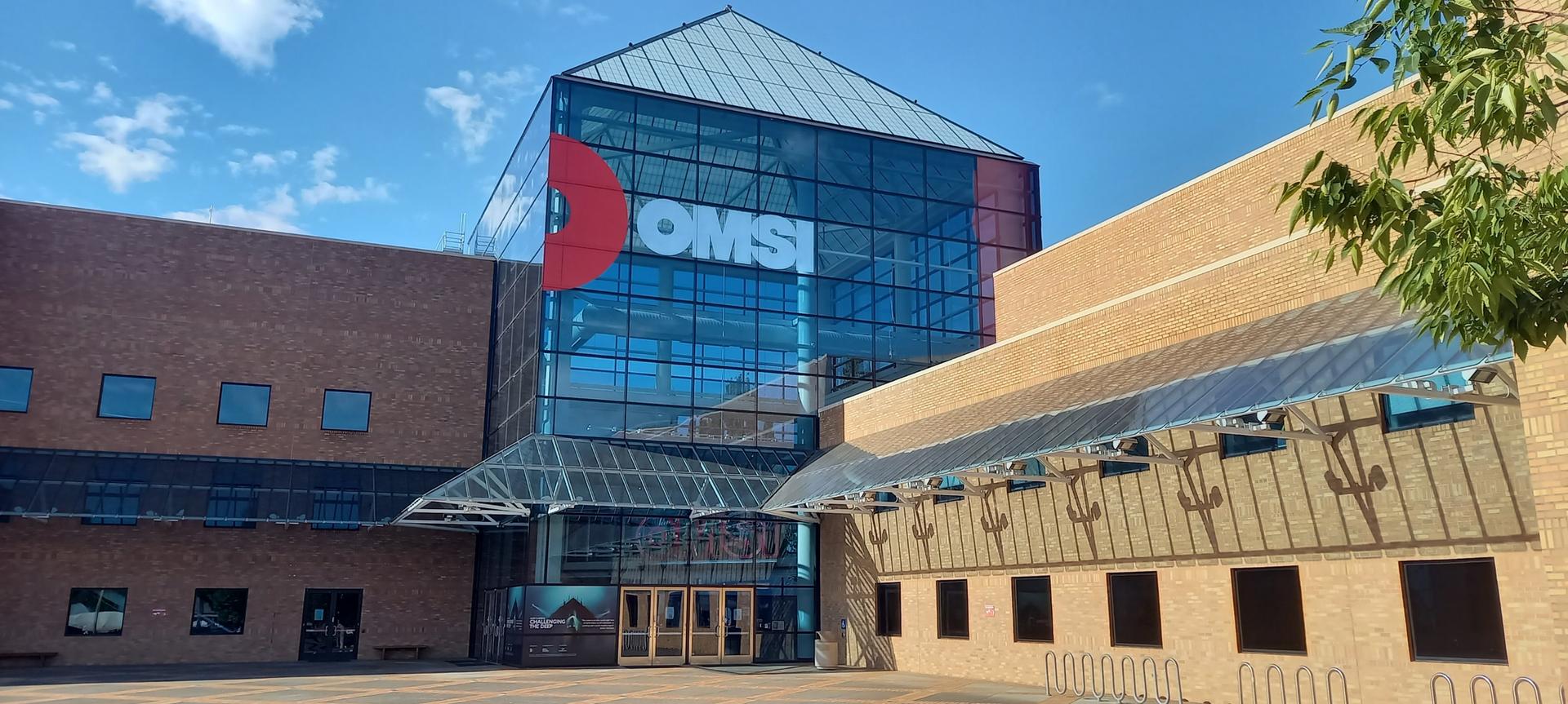 A large modern building with a glass and brick facade under a sunny sky.