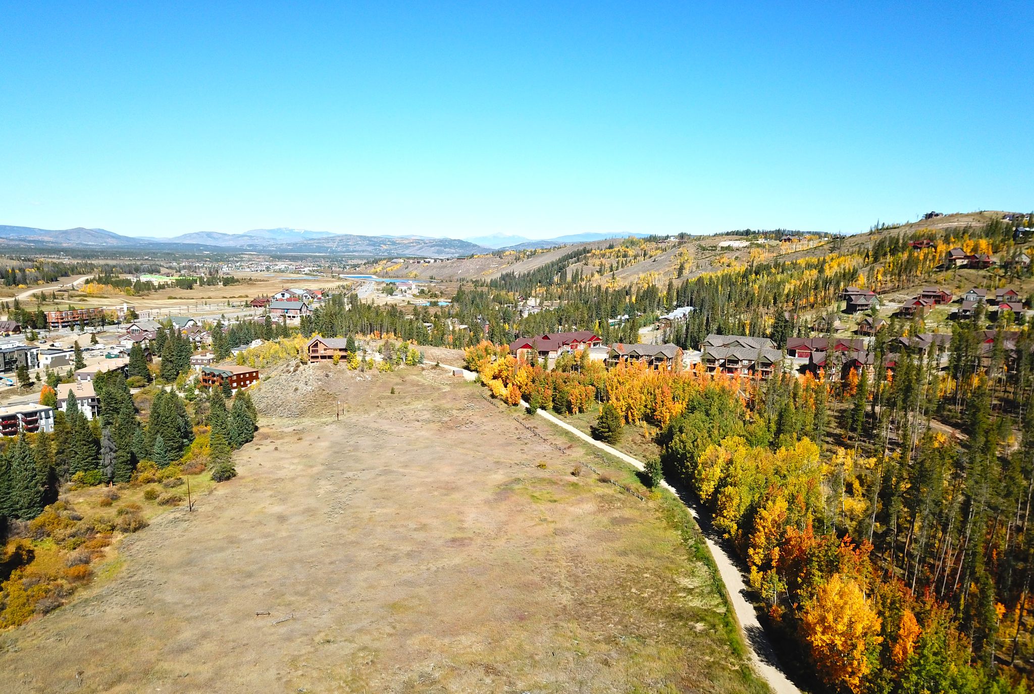 Aerial view of a valley with buildings and colorful autumn trees under blue sky. - Fraser River Trail loop from Winter Park