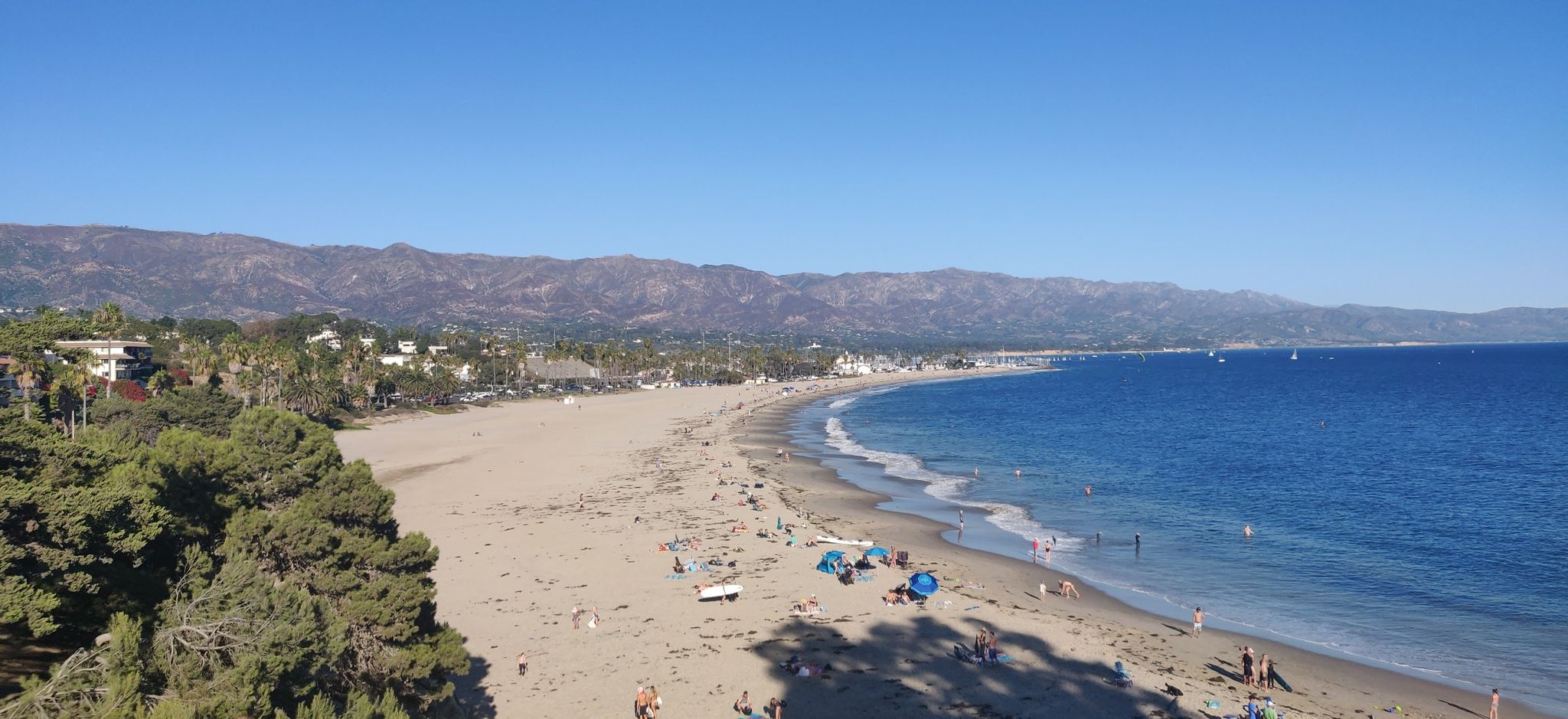 Aerial view of a sunny beach with blue ocean and distant mountains. - Hope Ranch Loop