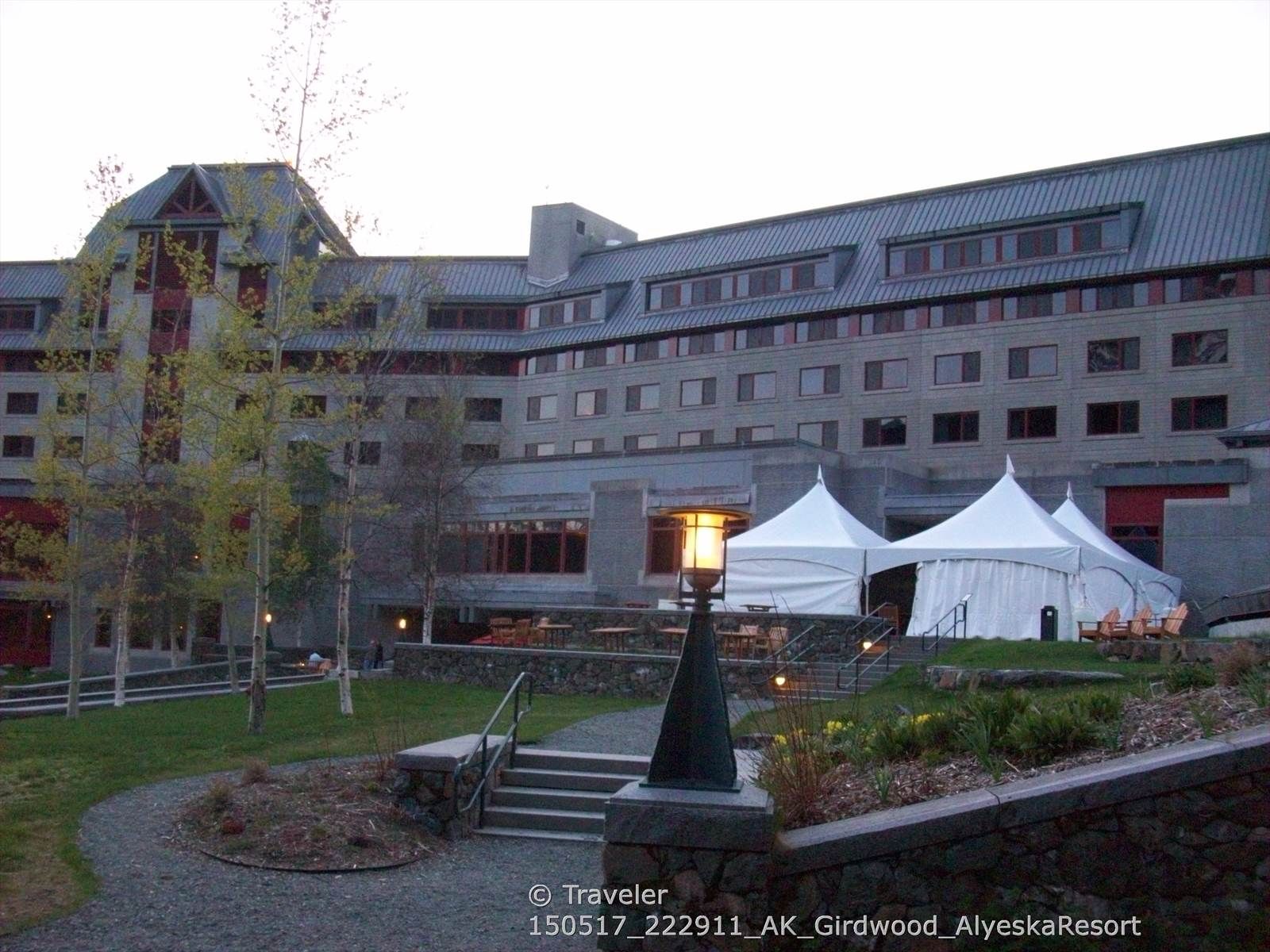Large hotel building with white event tents and outdoor lighting at dusk. - Moose Meadow Trail