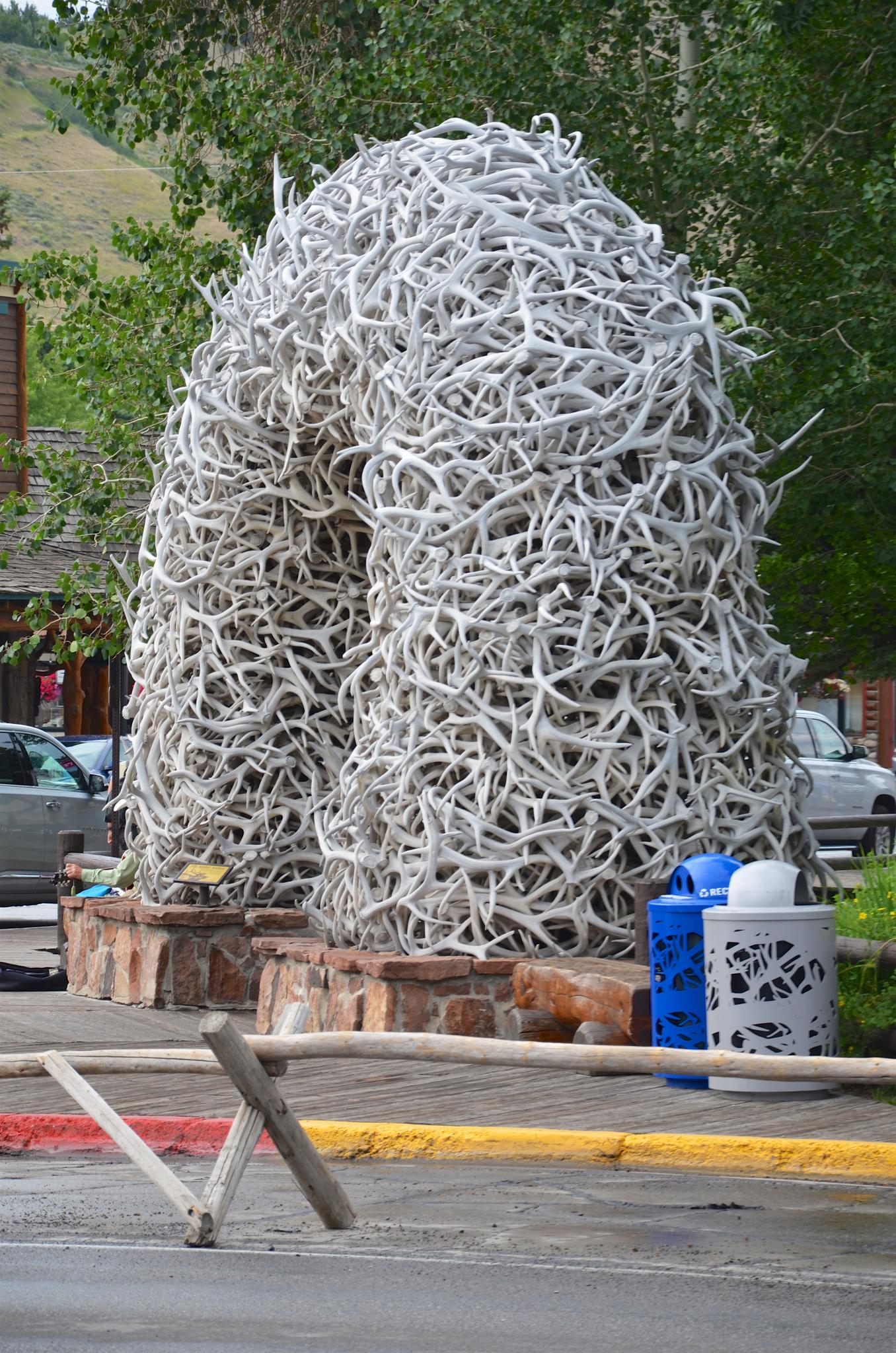 A large archway sculpture made of many antlers stands in a town square.