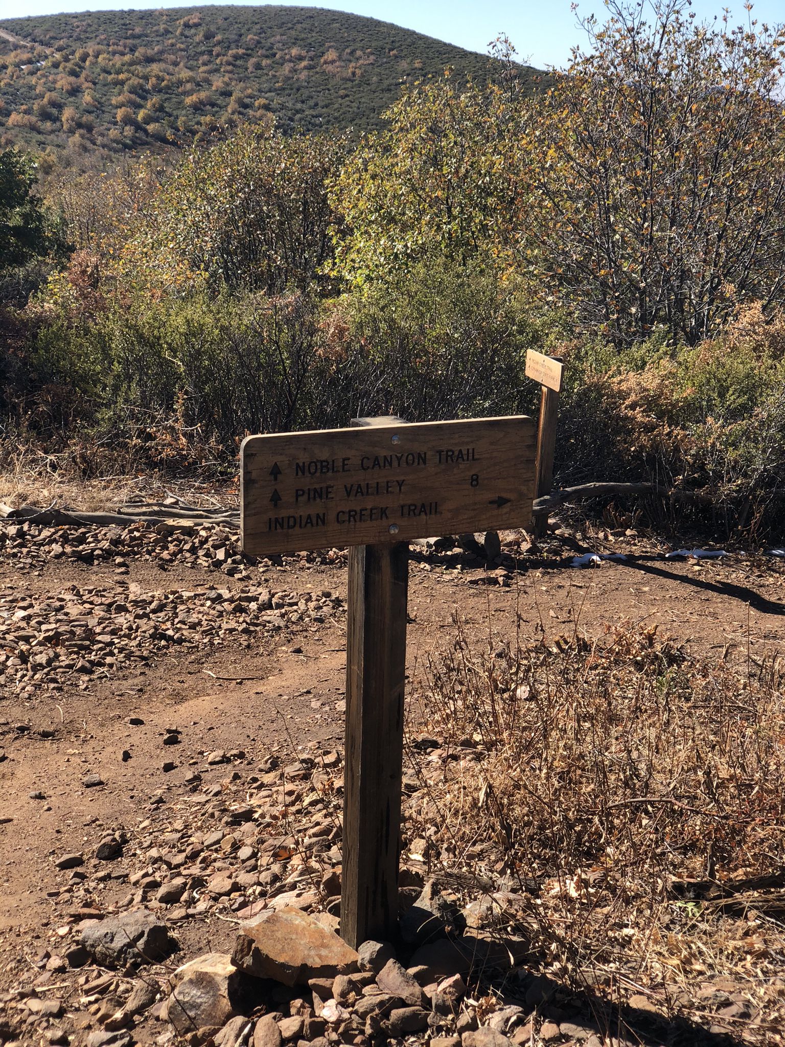 A wooden trail signpost stands on a dry, rocky path under bright sun. - Cuyamaca Rancho State Park and Noble Canyon loop via East Mesa Fire Road