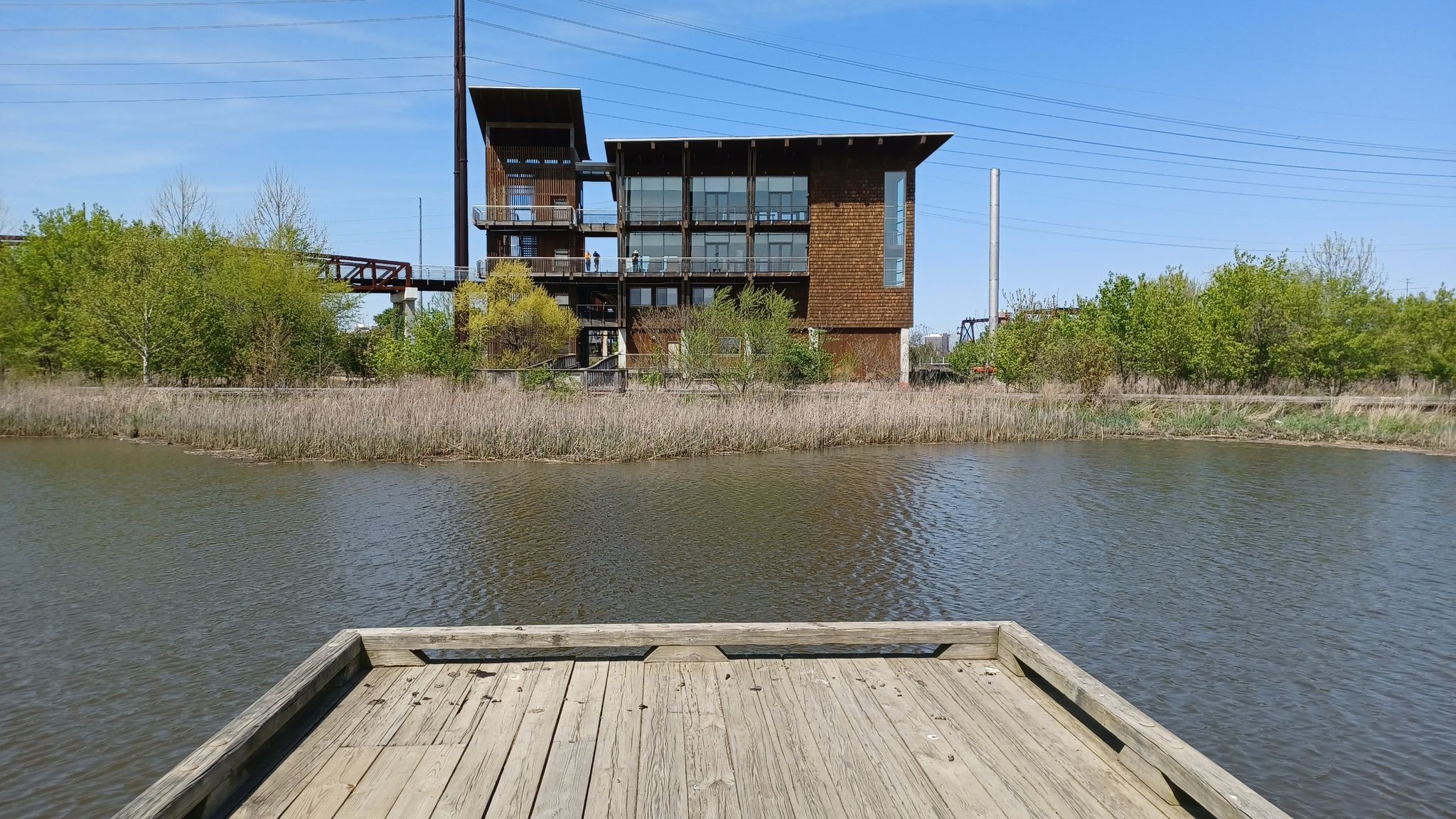 A wooden dock extends into a river, with an industrial building in the background. - Running loop from Wilmington