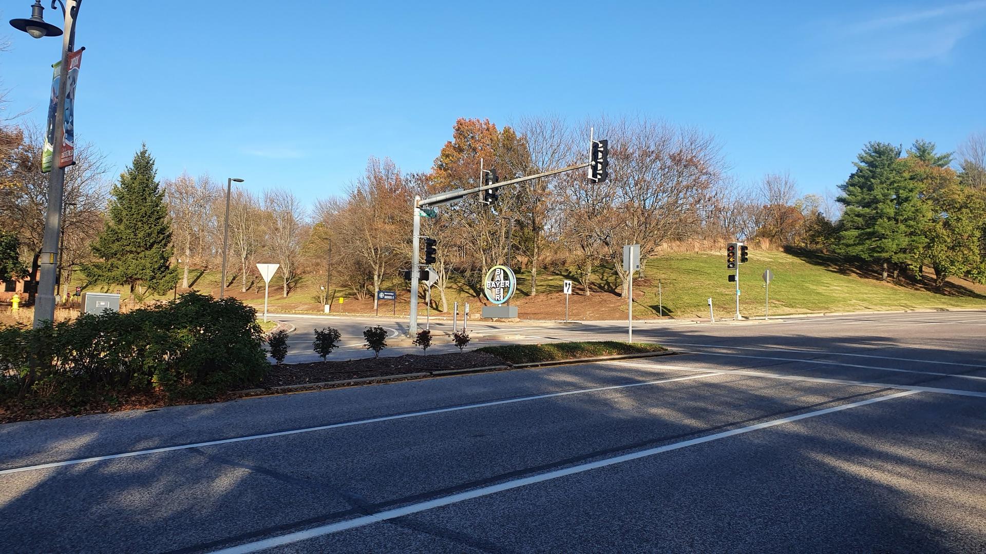 A wide road intersection with traffic lights under a clear blue sky.