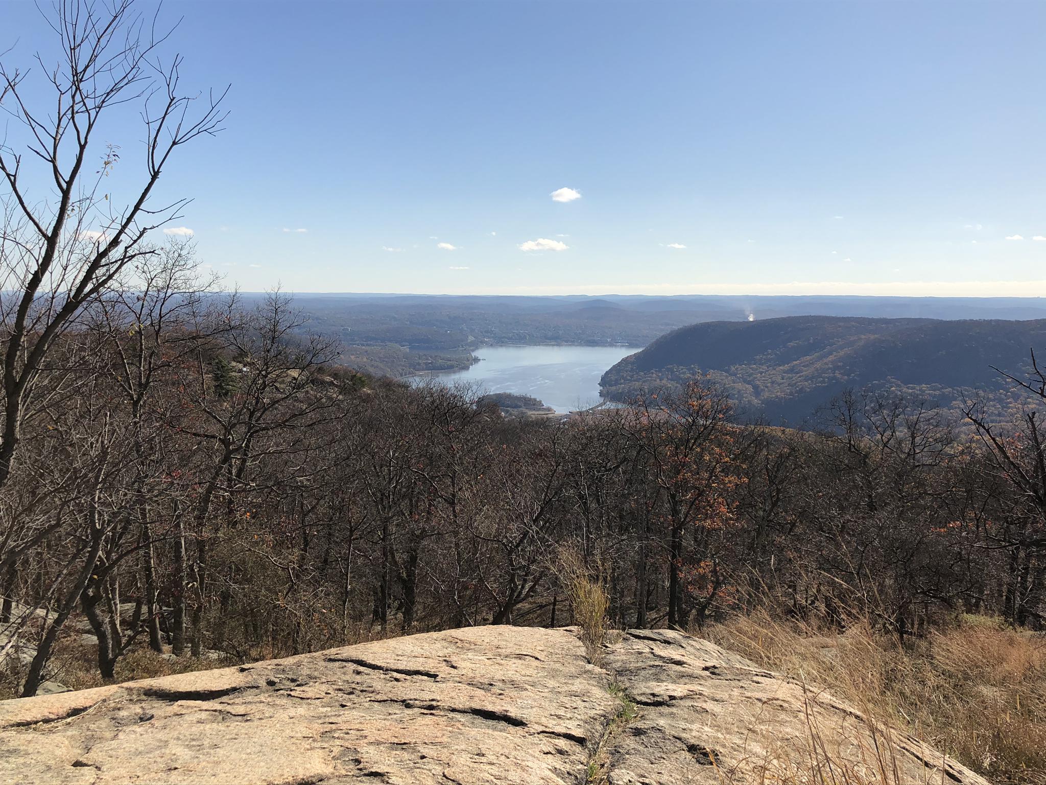 Expansive view of a wide river through a wooded valley from a rocky overlook.