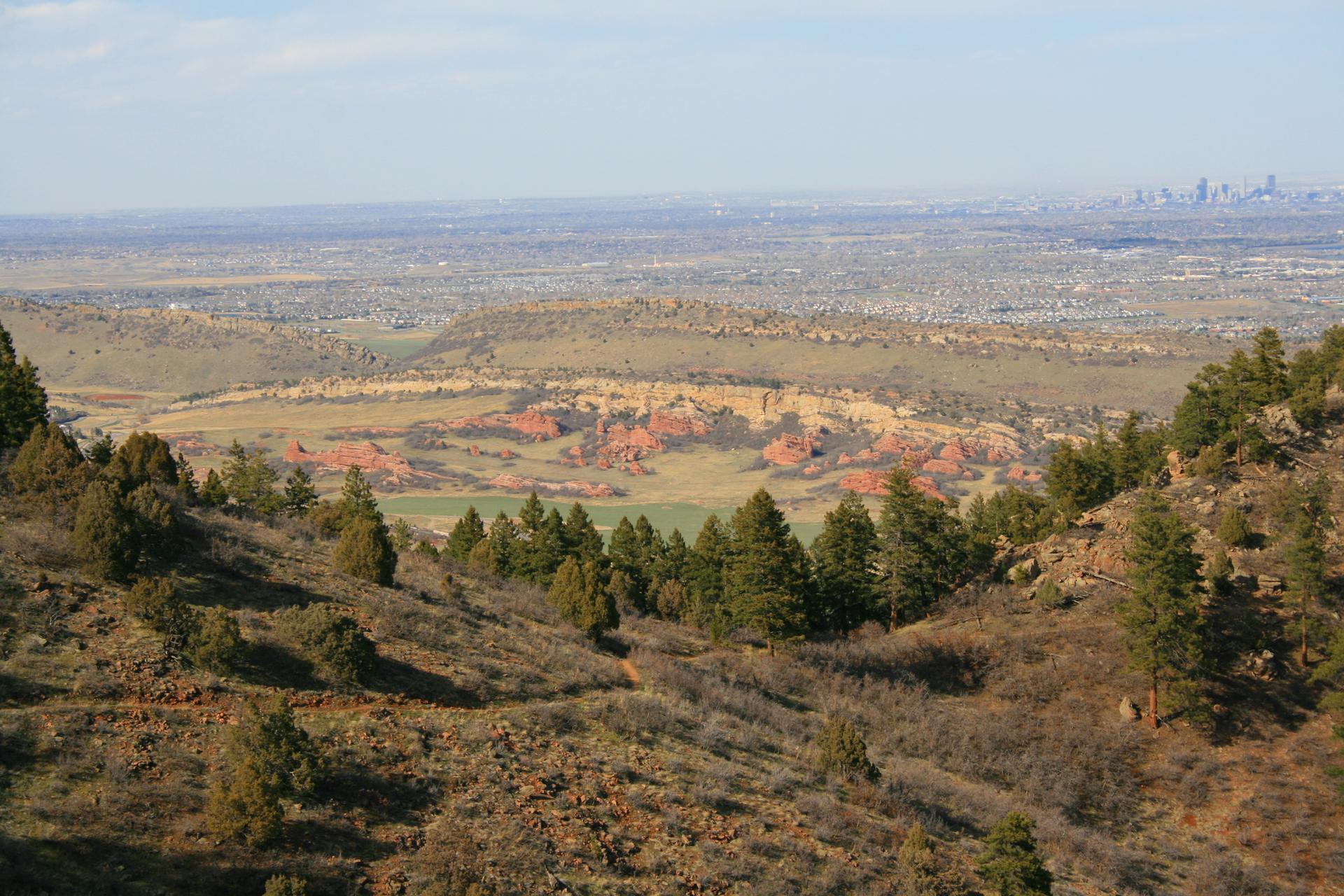 Bright view of a valley with colorful rock formations and a distant city.
