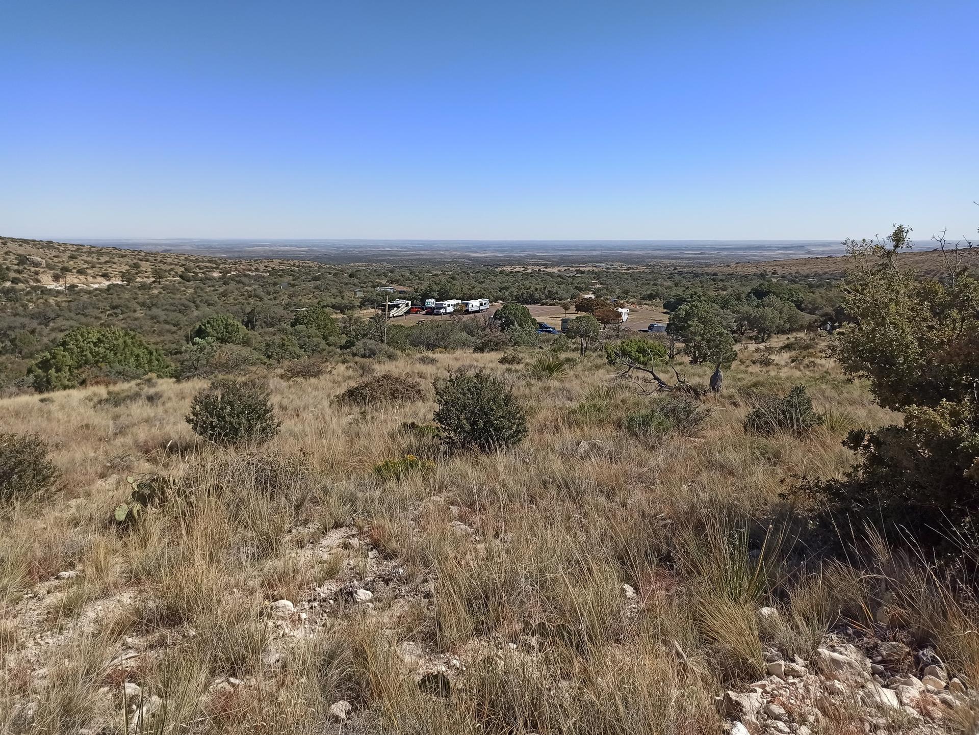A wide view of a desert landscape with RVs parked in the distance.