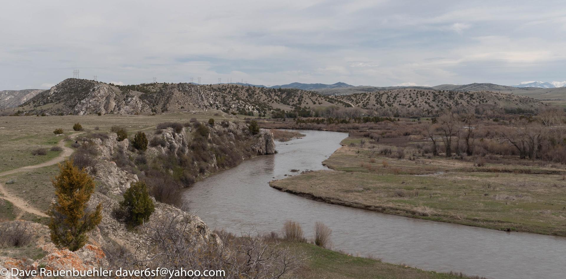 Wide river flowing through arid, rocky hills and sparse vegetation.