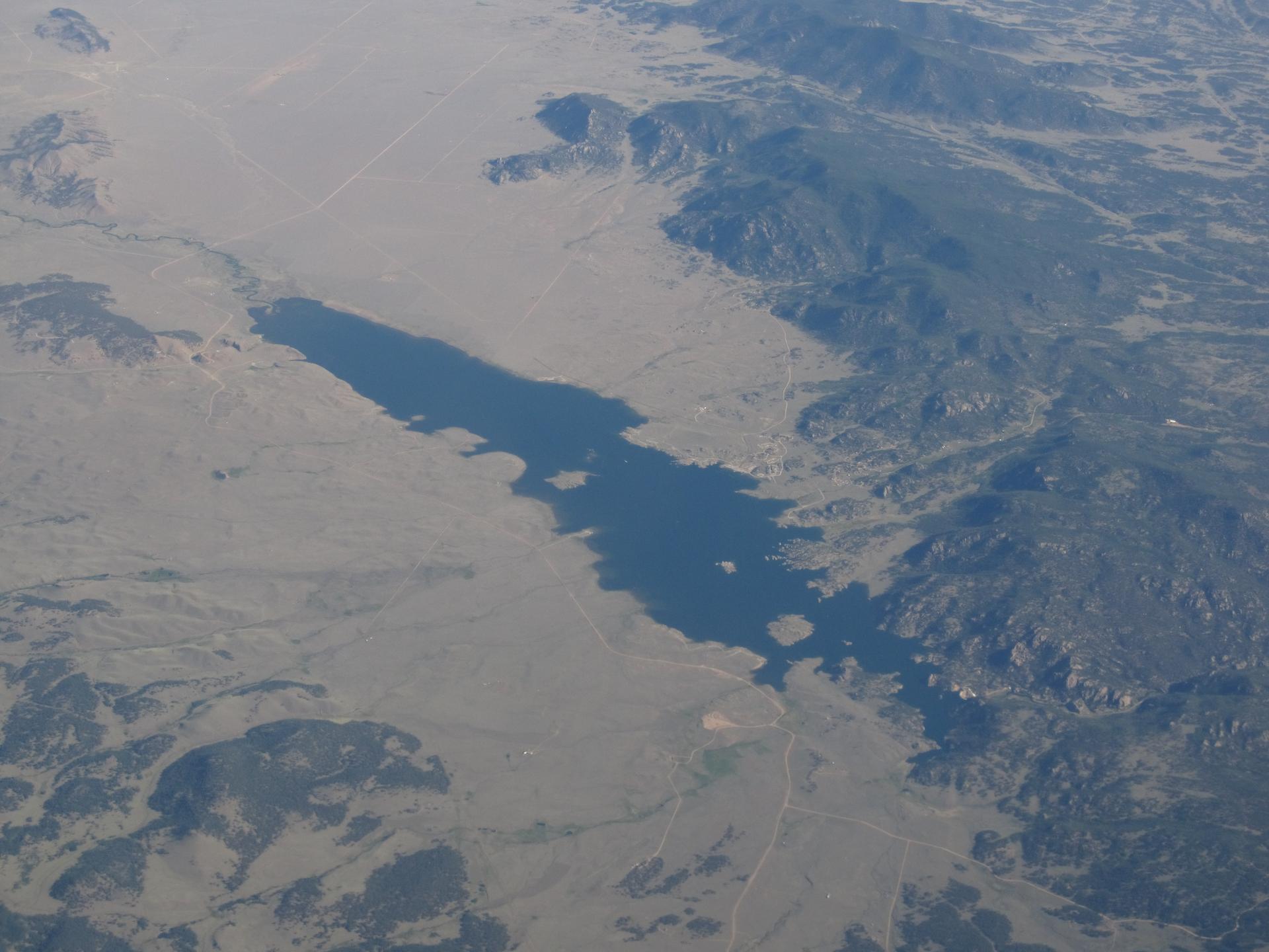 Aerial view of a long lake surrounded by dry, mountainous terrain.
