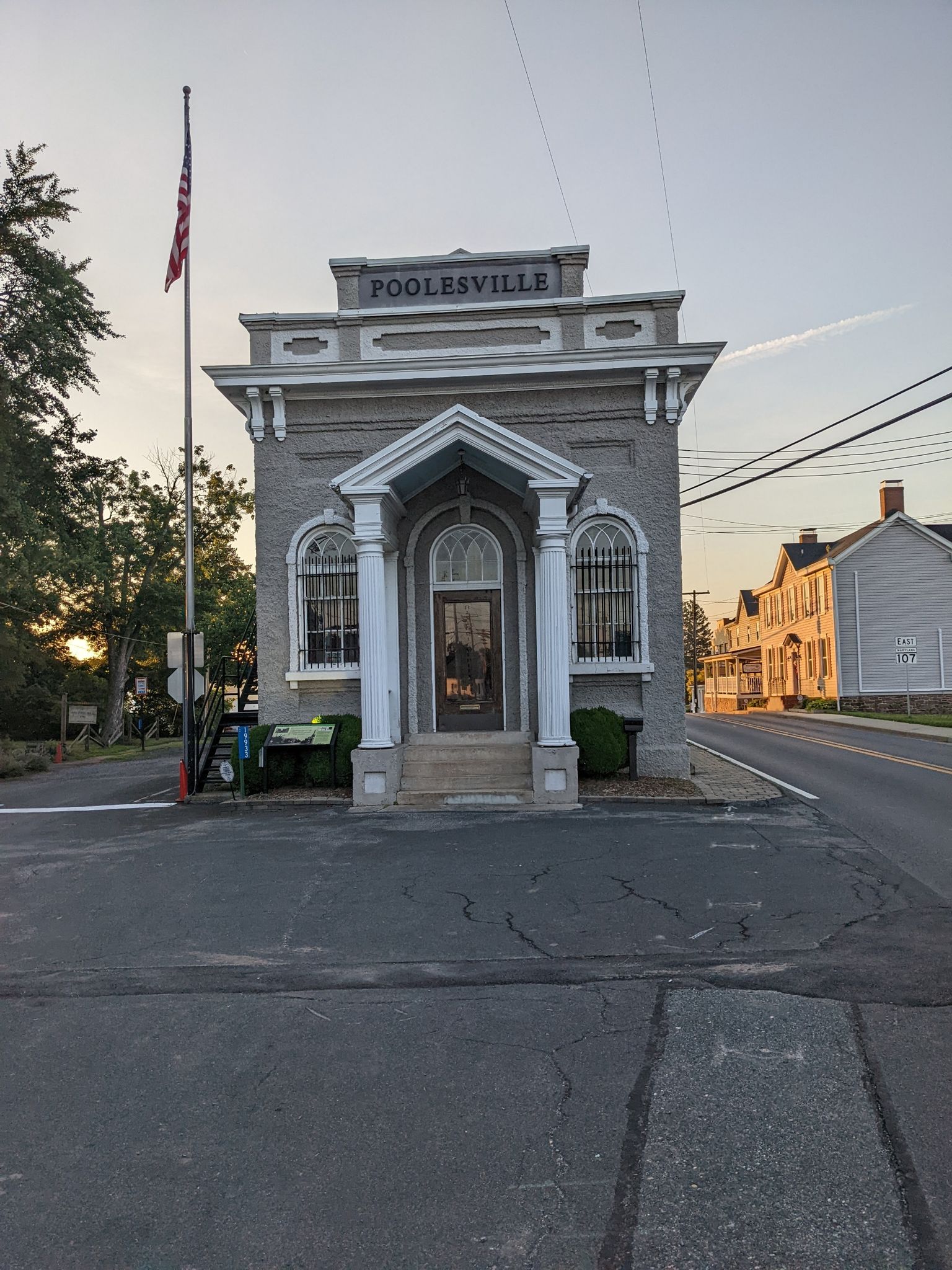 Ornate grey building with a flagpole at sunset, empty street in foreground. - Montevideo Road – Seneca Schoolhouse loop from Seneca