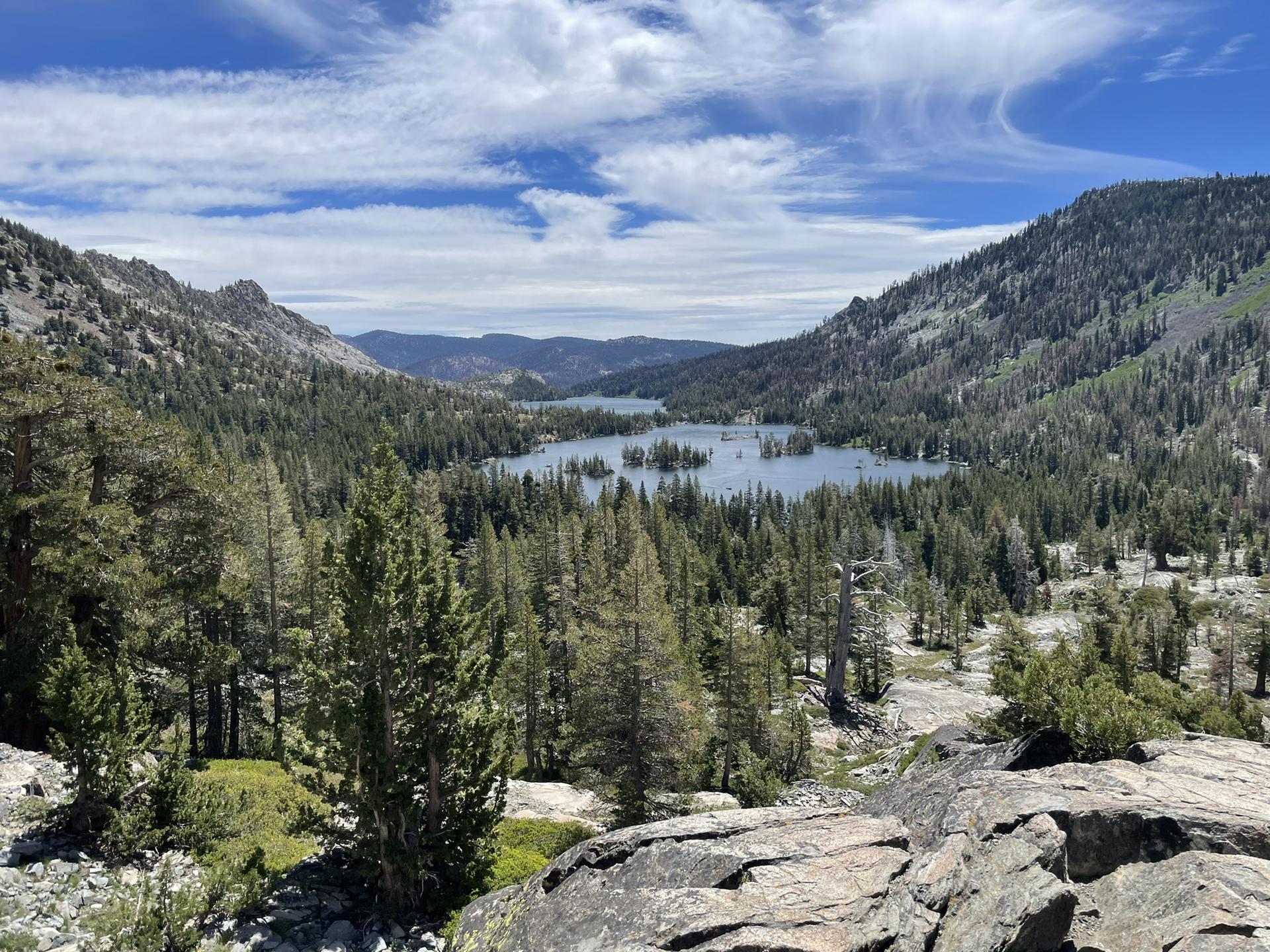 Panoramic view of multiple lakes nestled in a vast forested valley under clouds.