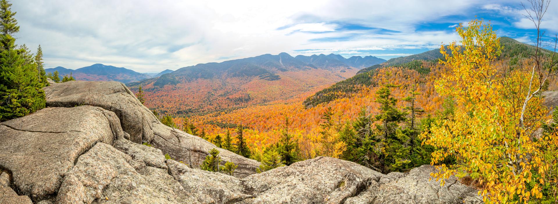 Panoramic view of mountains and valleys ablaze with vibrant autumn colors.